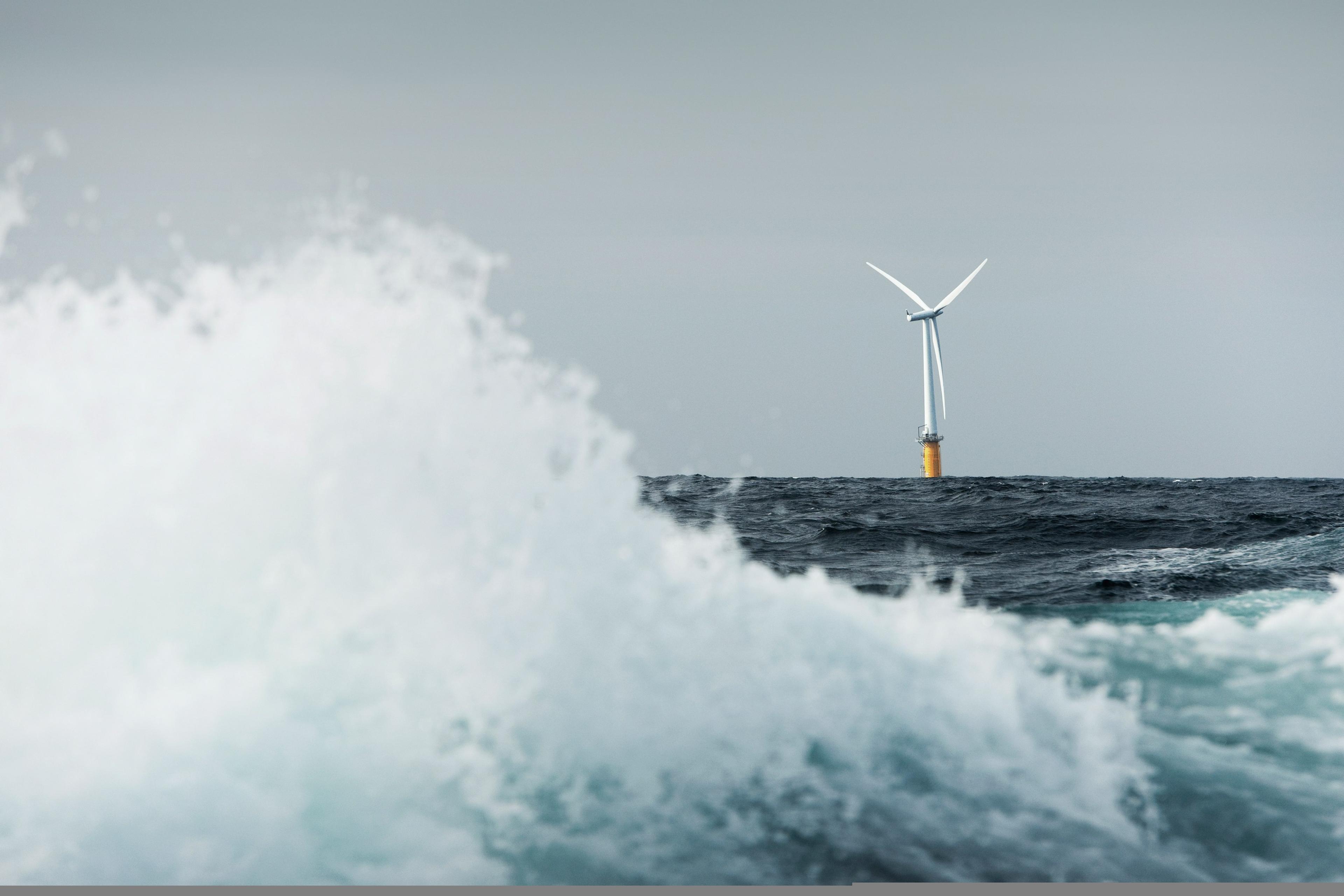 Floating offshore wind turbine, with a large wave in the foreground