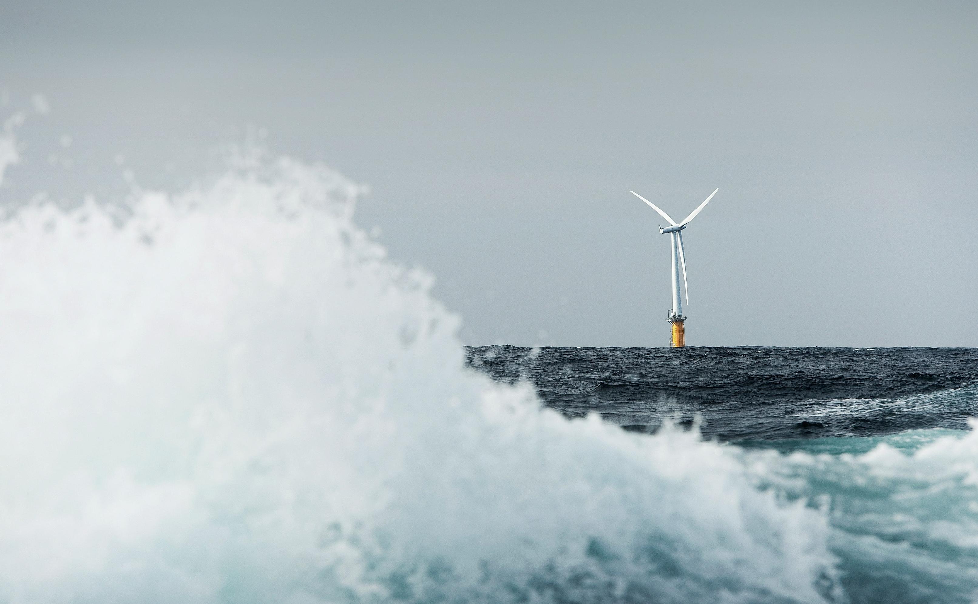 Floating offshore wind turbine, with a large wave in the foreground