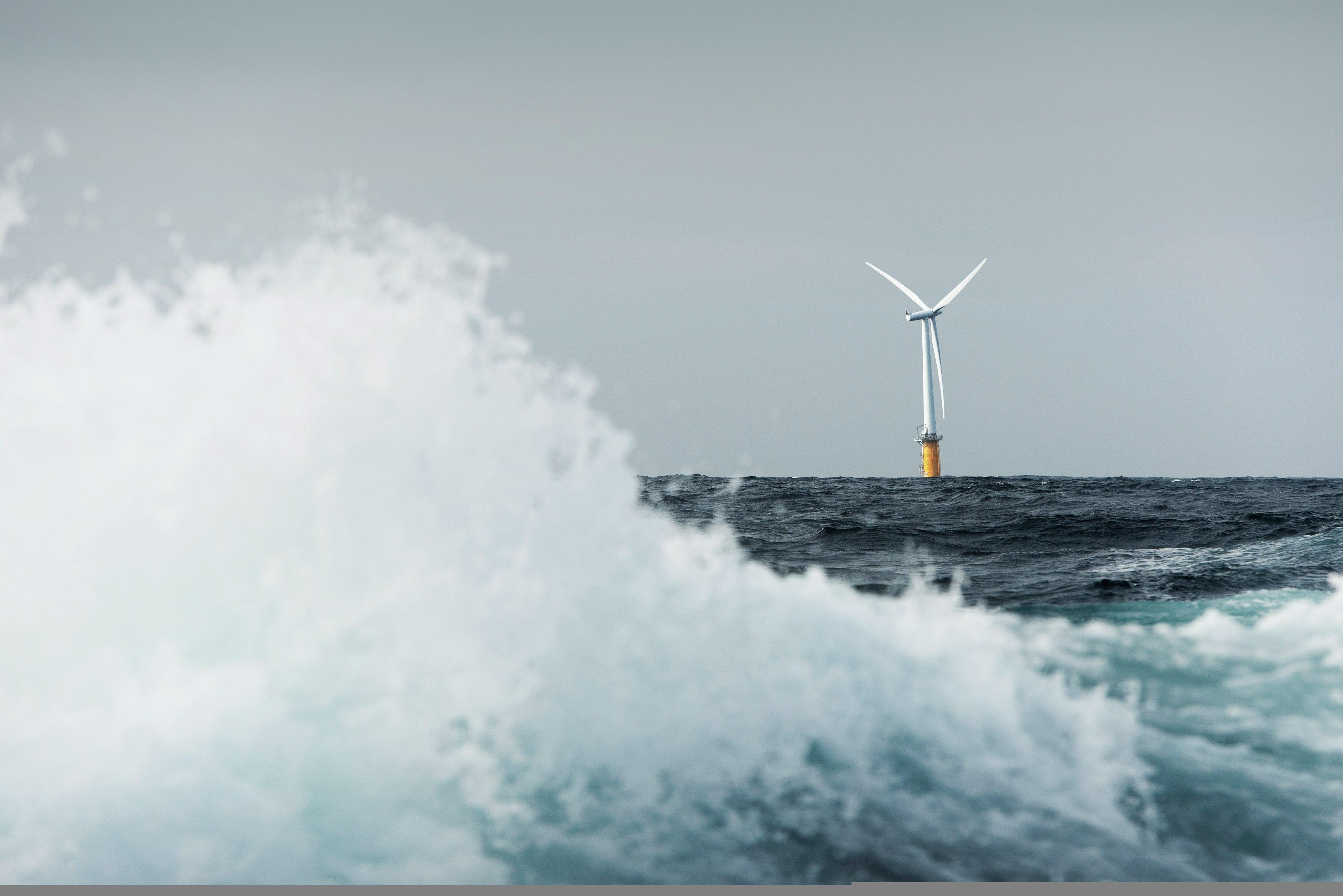 Floating offshore wind turbine, with a large wave in the foreground