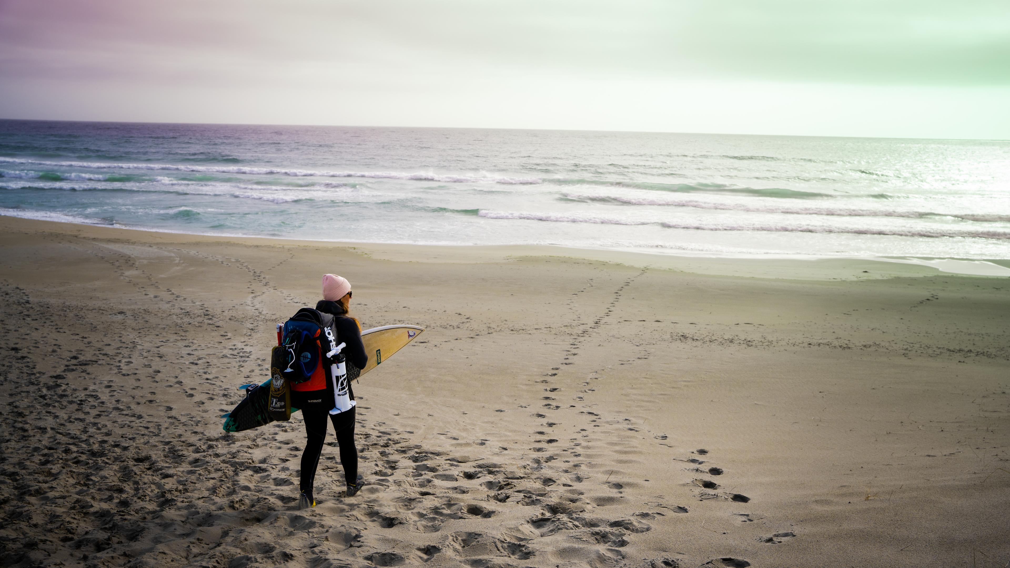 A woman carrying kiting gear at the beach outside of Stavanger, Fjord Norway.