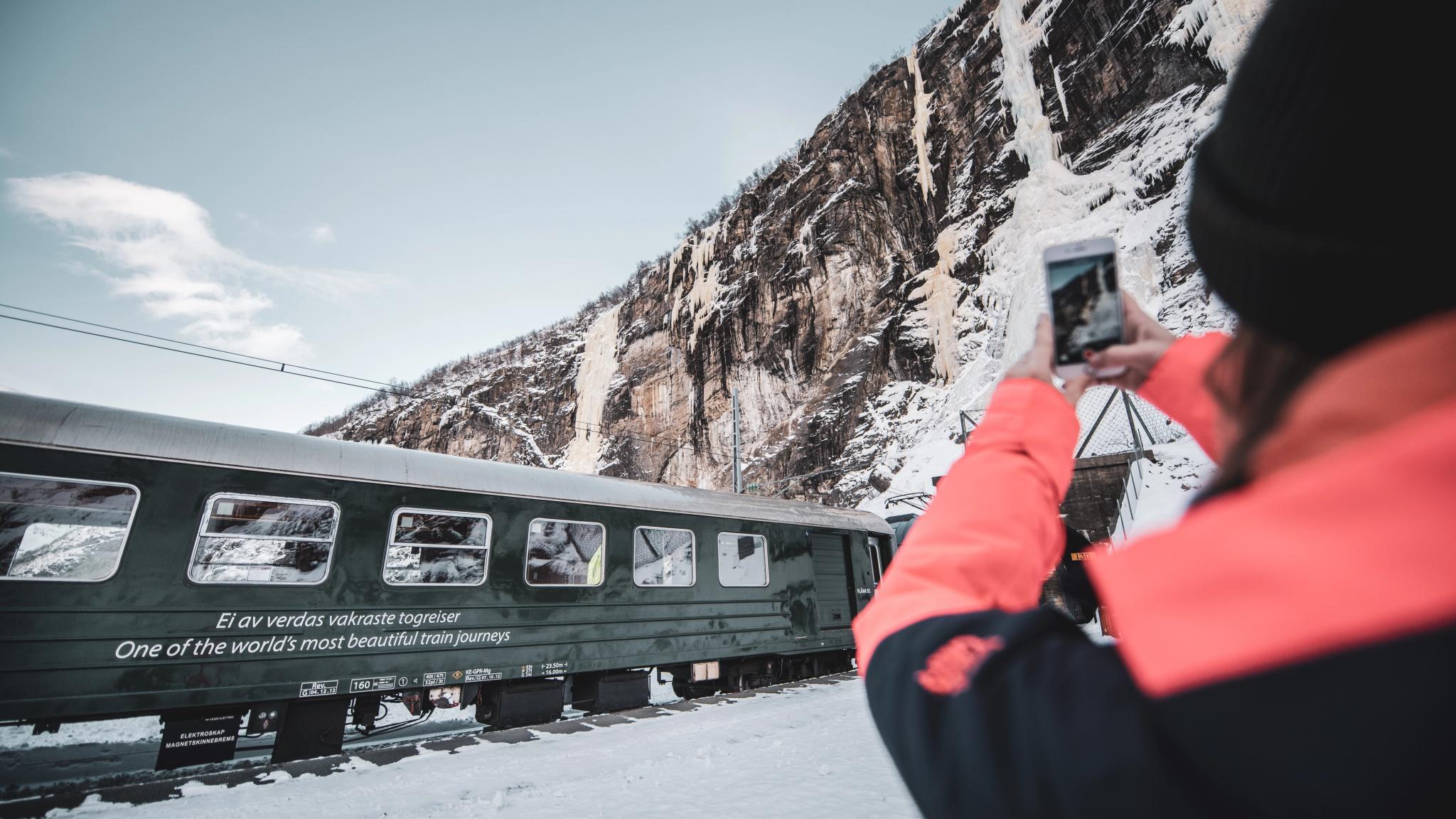 A woman taking a picture of the Flåmsbana train