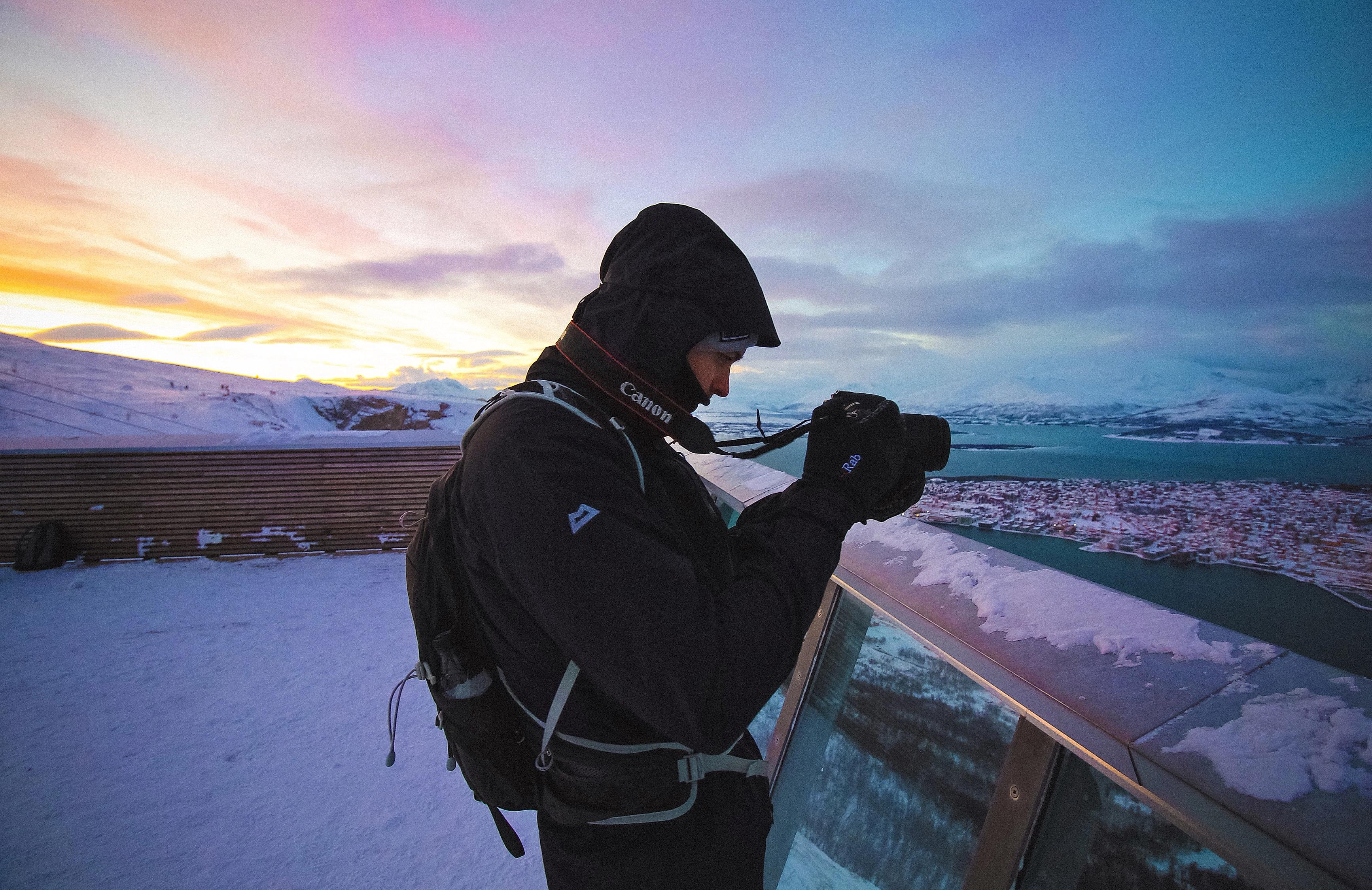 A tourist taking pictures from the top point of the gondola, Fjellheisen in Tromsø