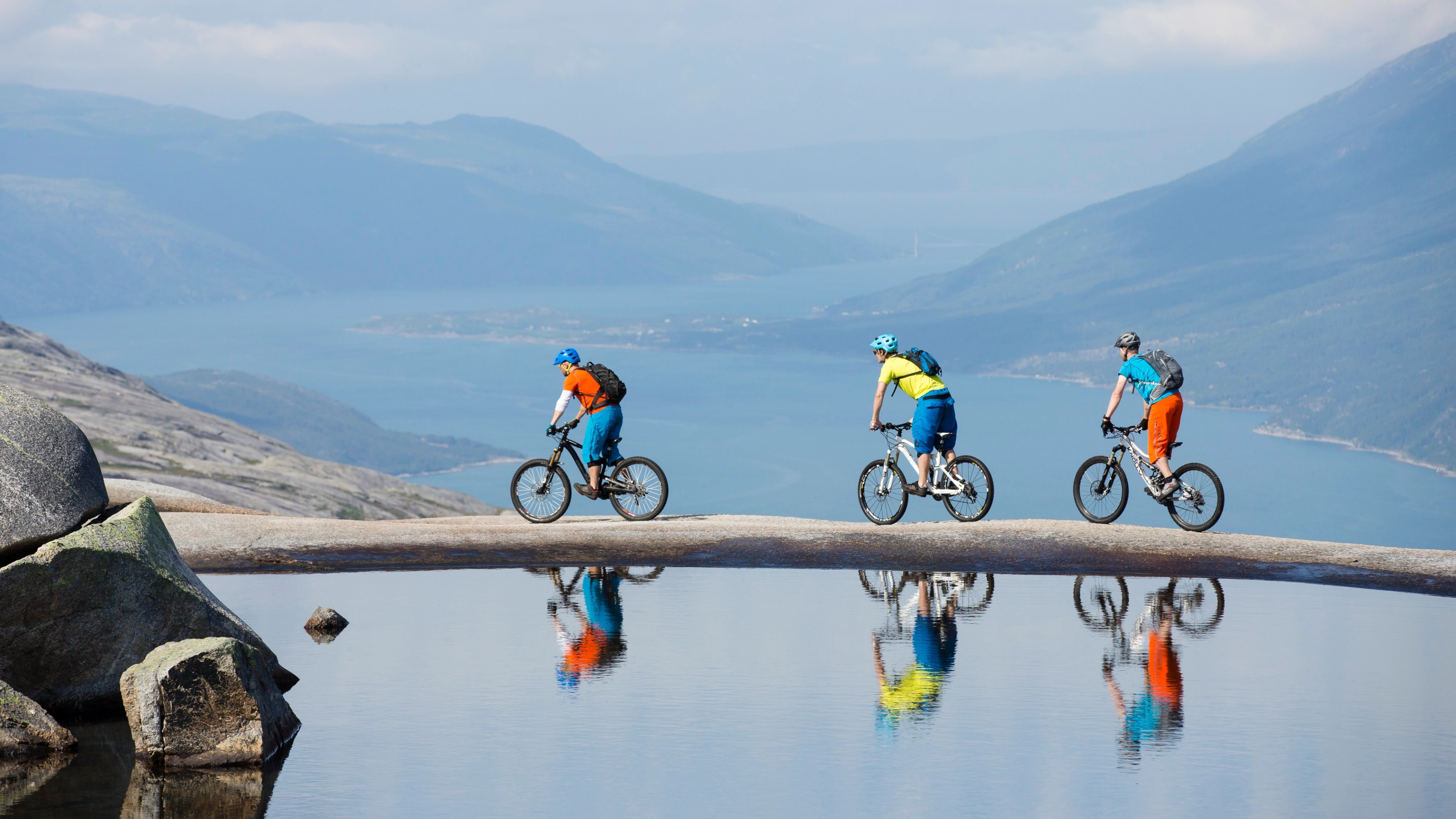 Three people mountain biking along a small lake in the Reinnesfjellet mountains in Narvik, Northern Norway