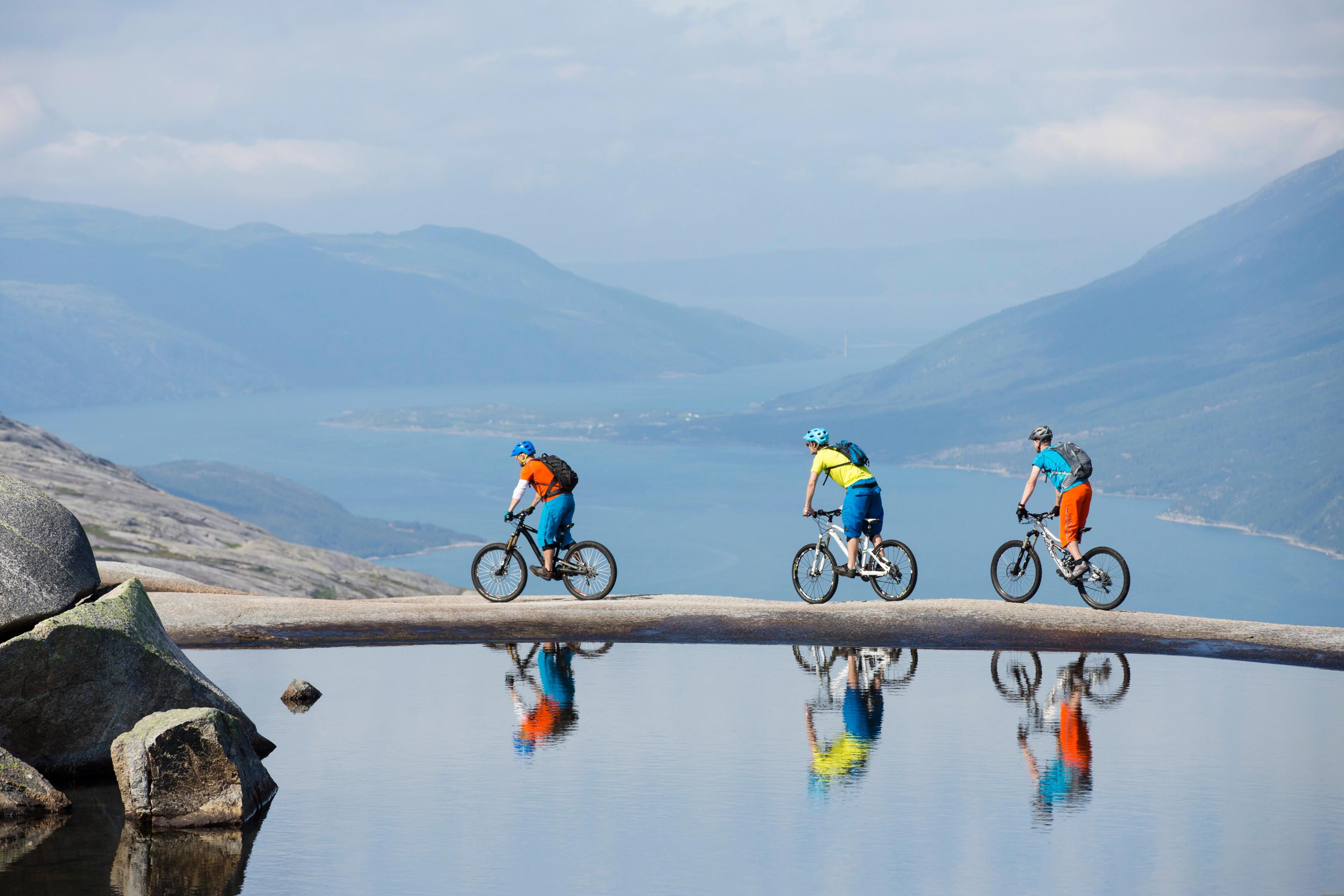 Three people mountain biking along a small lake in the Reinnesfjellet mountains in Narvik, Northern Norway