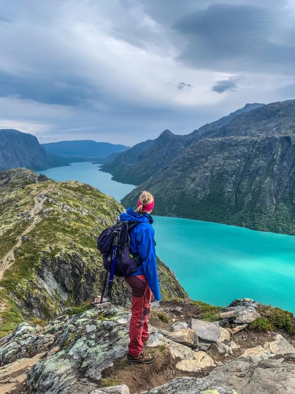 A woman hiking and looking at the Gjendevatnet lake