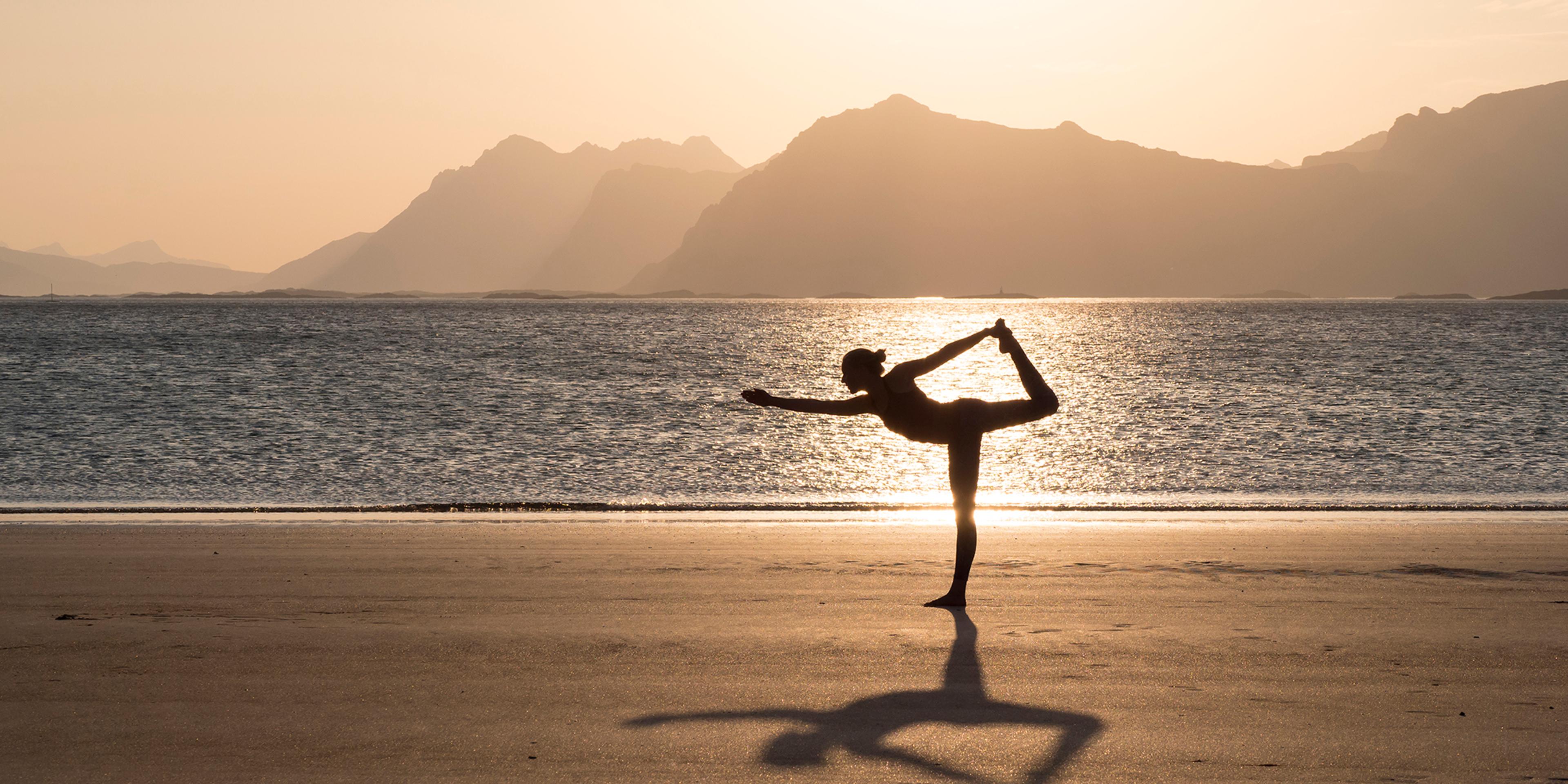 Una mujer practica yoga en silencio en una playa en Lofoten, Norte de Noruega.