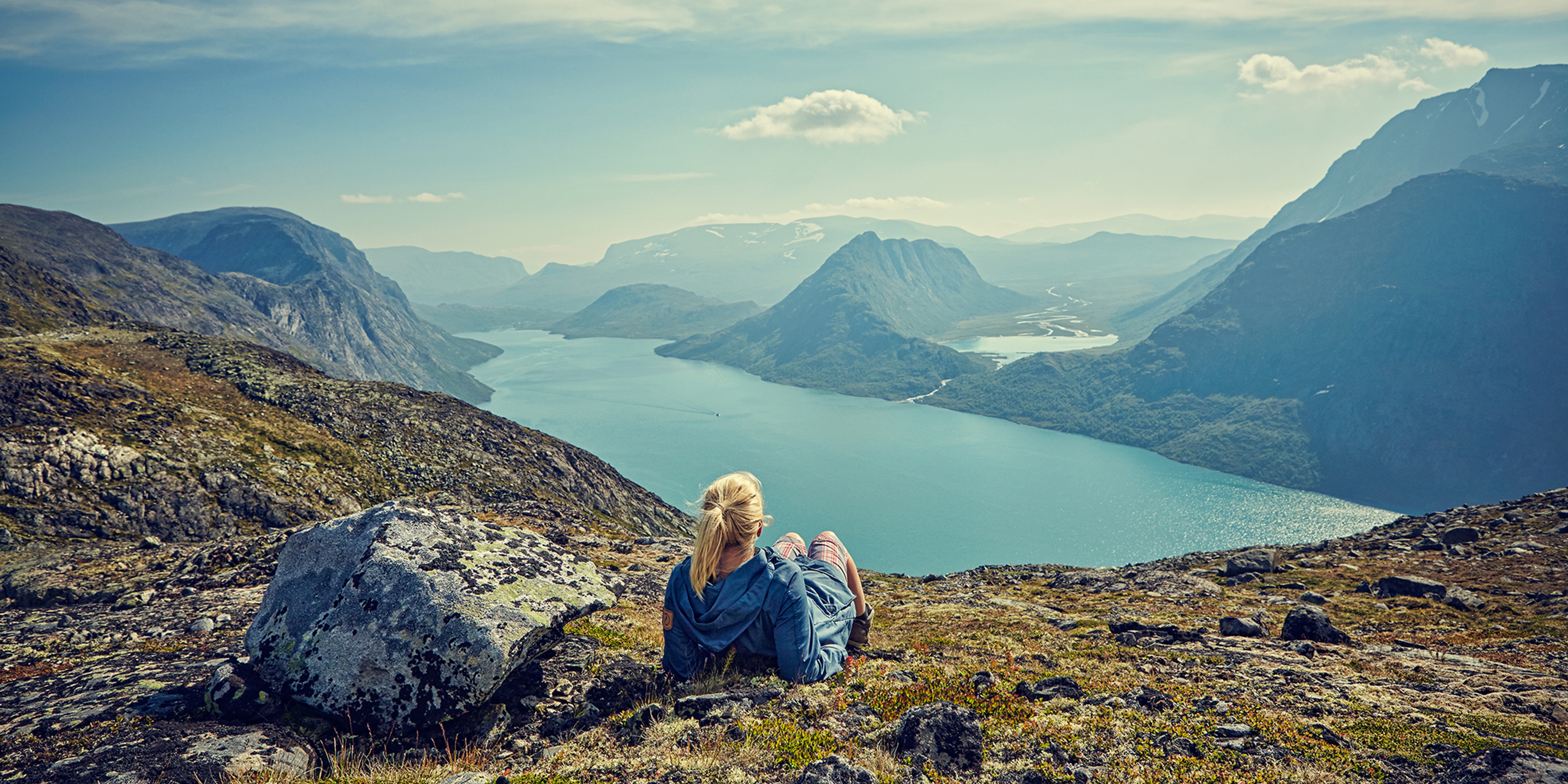 En vandrare blickar ut över sjön Gjende i Jotunheimen