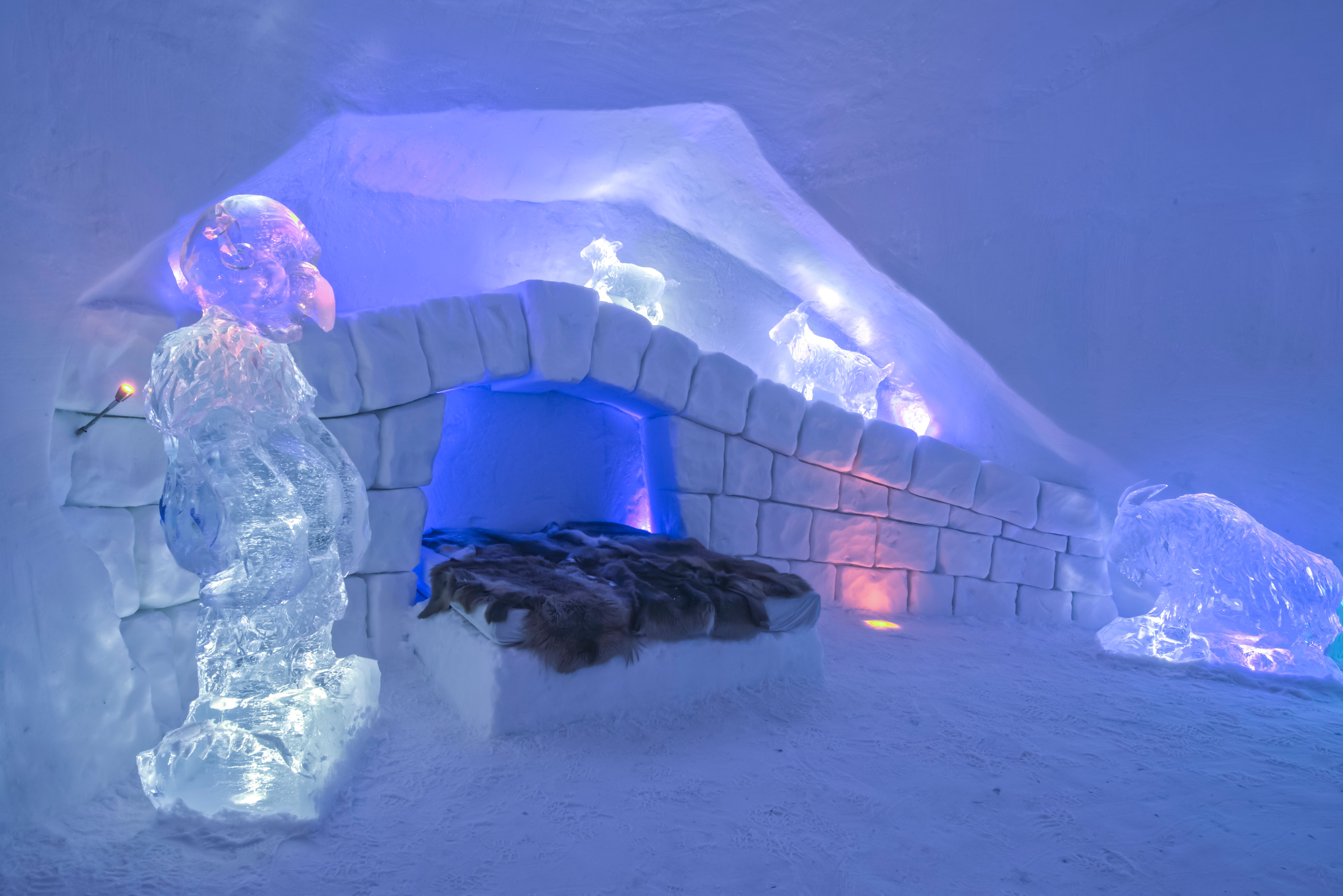 A bed and ice culptures inside Hunderfossen Snow Hotel