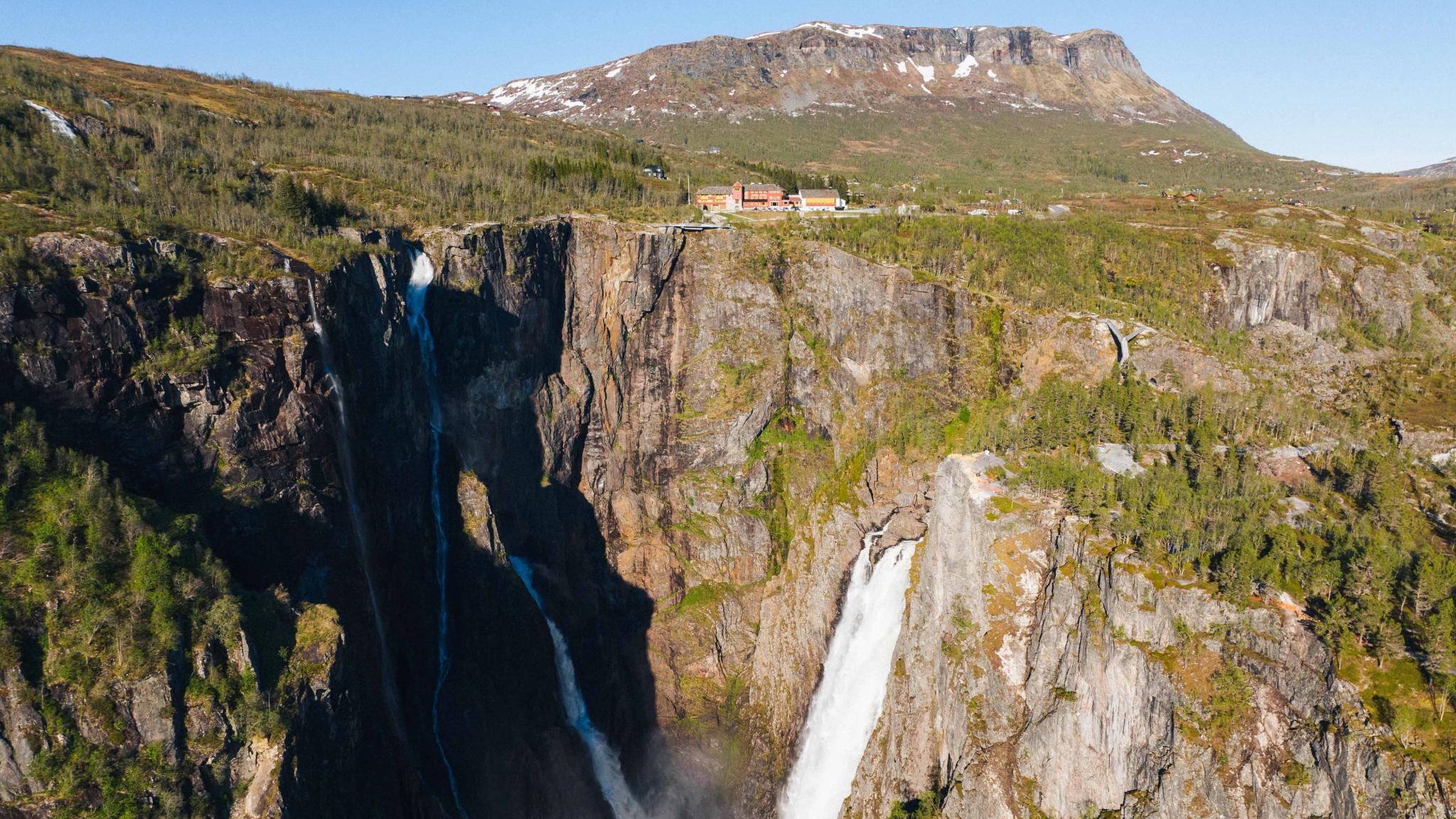 A huge waterfall and a building on a mountain ledge
