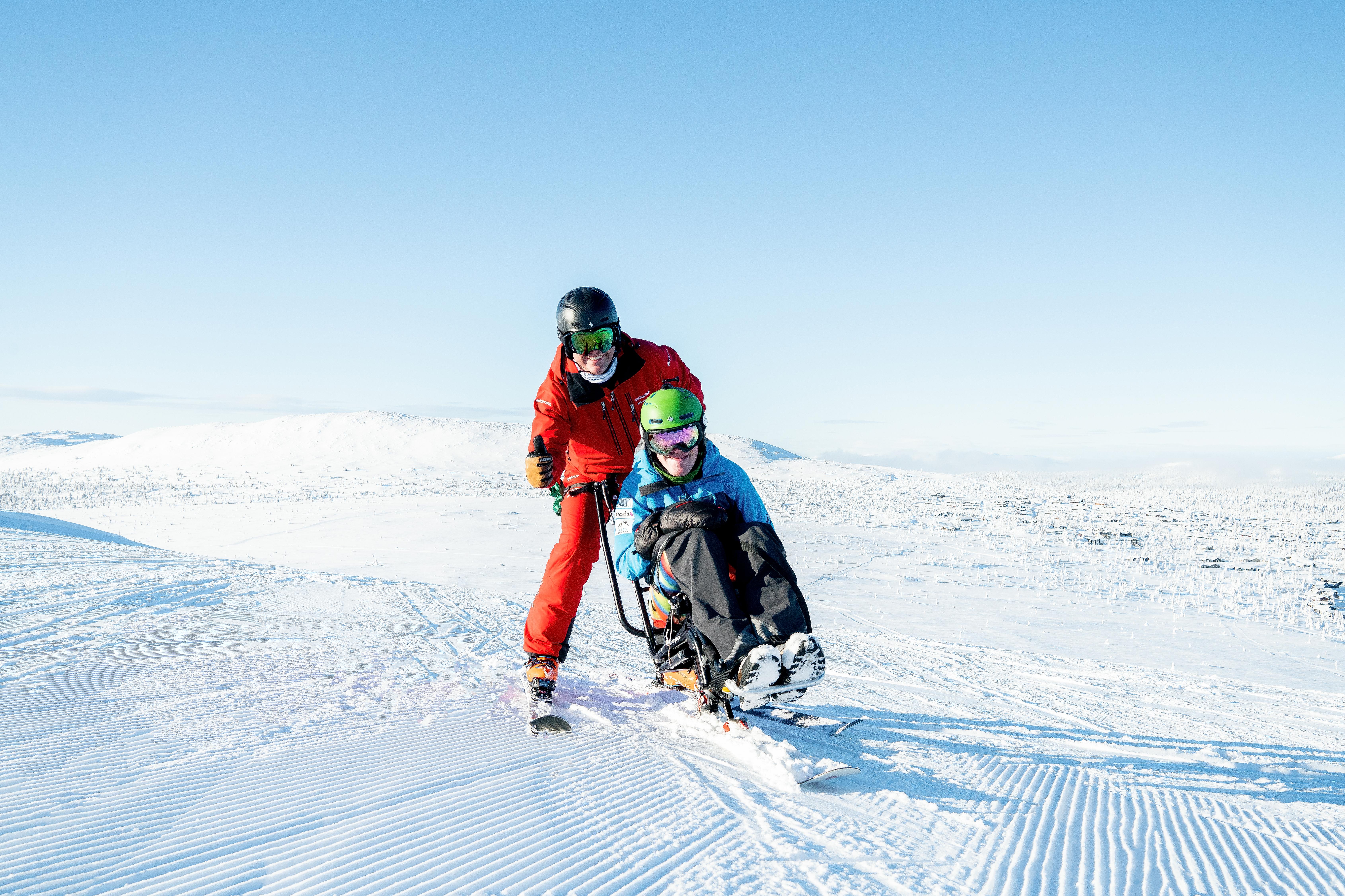 Person på sitski sammen med ledsager