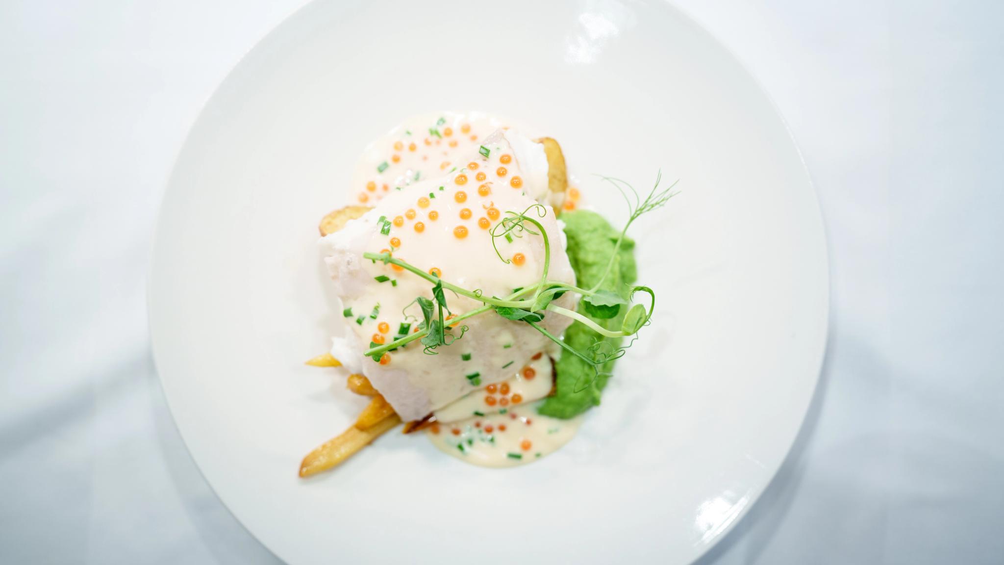 En fint anrettet tallerken med kveite, potet, ertepuree og hvit saus