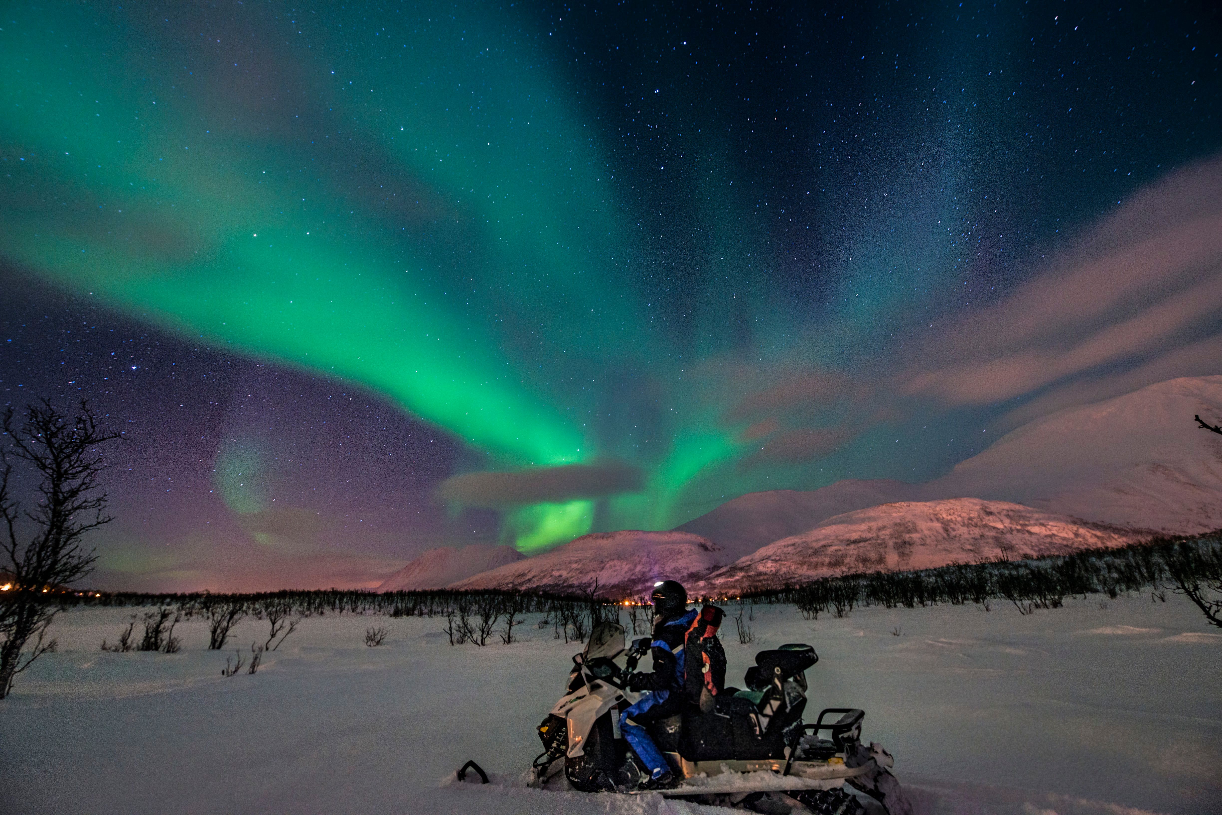 Man on a snowmobile under the northern lights
