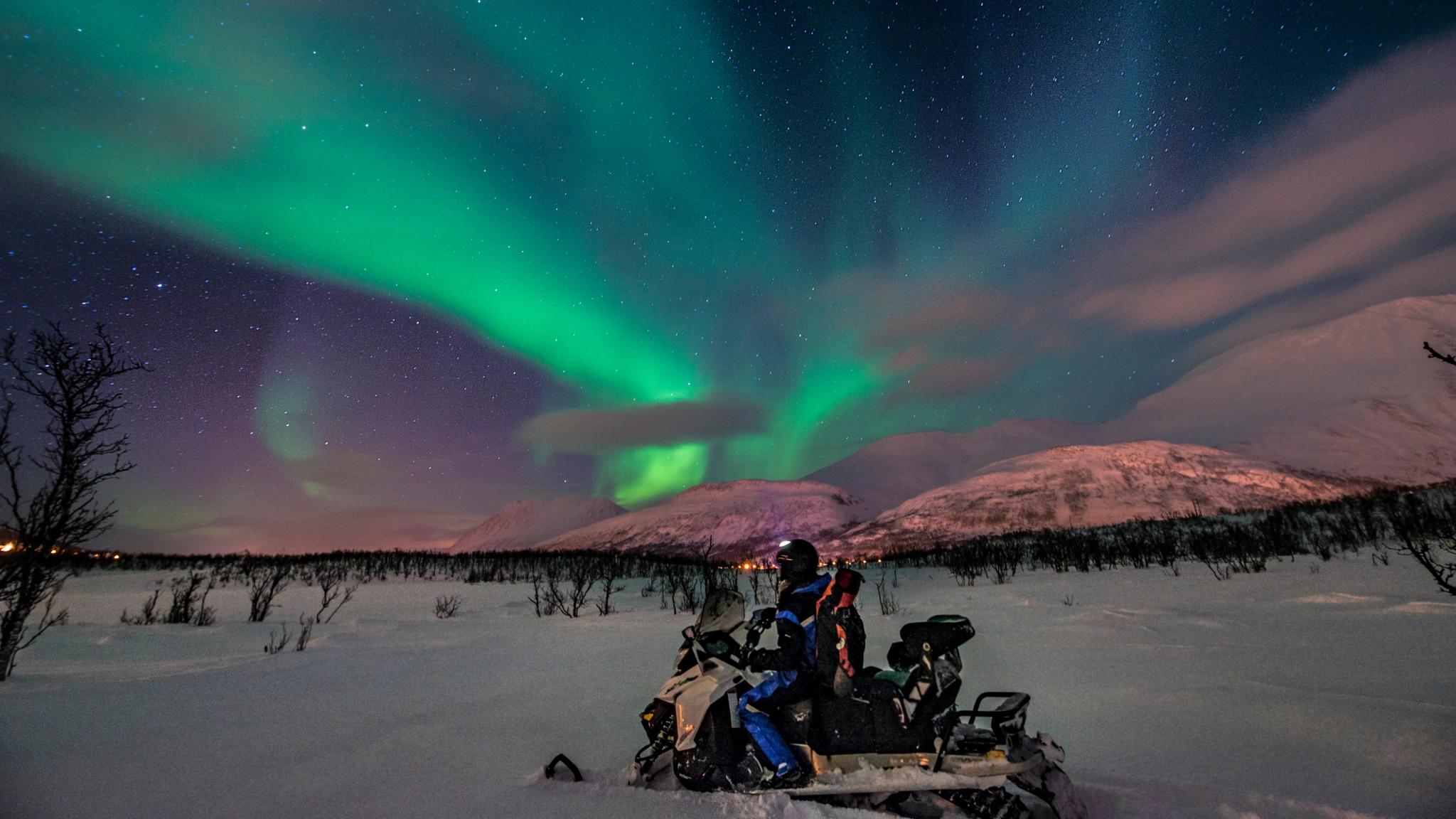 Man on a snowmobile under the northern lights
