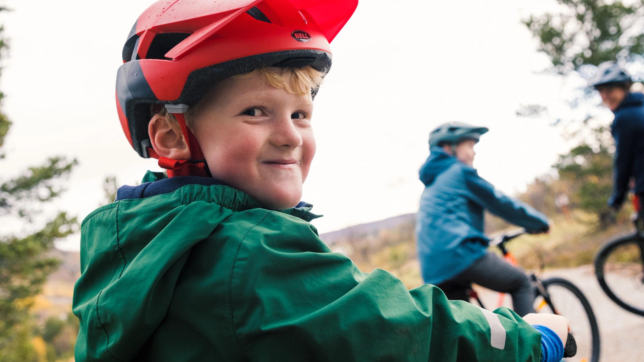 Young boy smiling while biking with his family in Geilo.