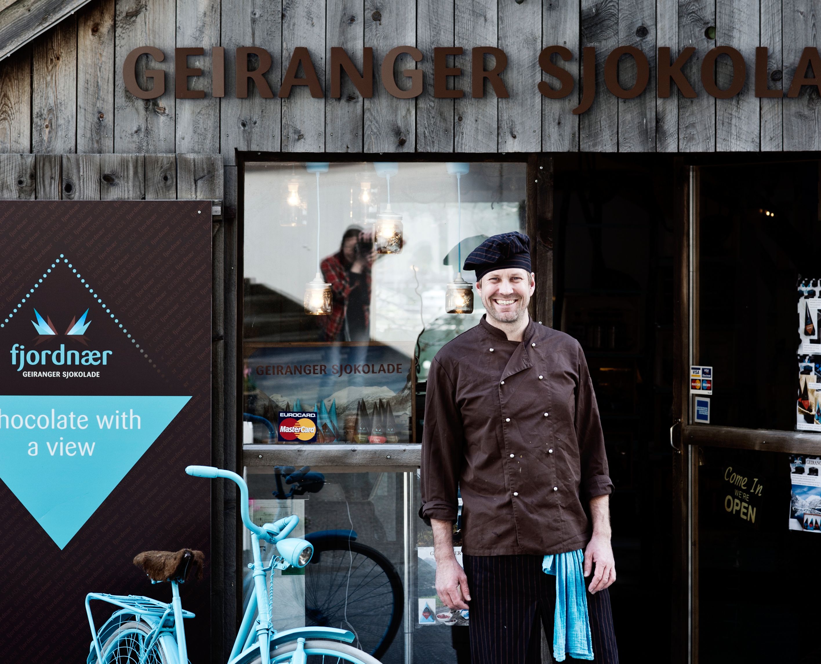 A man standing outside of the Geiranger chocolate factory, Norway.