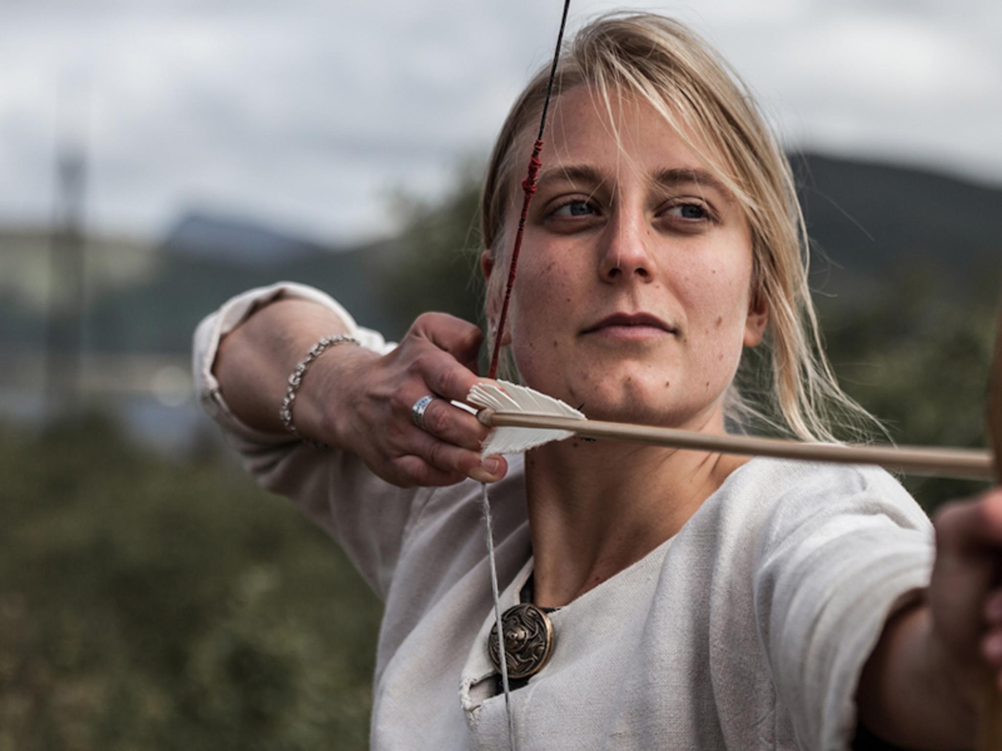 En dame skyter med pil og bue på Lofotr Vikingmuseum på Borg, en av Norges største vikingopplevelser