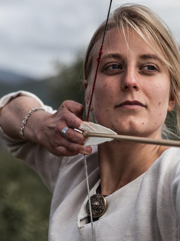 En dame skyter med pil og bue på Lofotr Vikingmuseum på Borg, en av Norges største vikingopplevelser