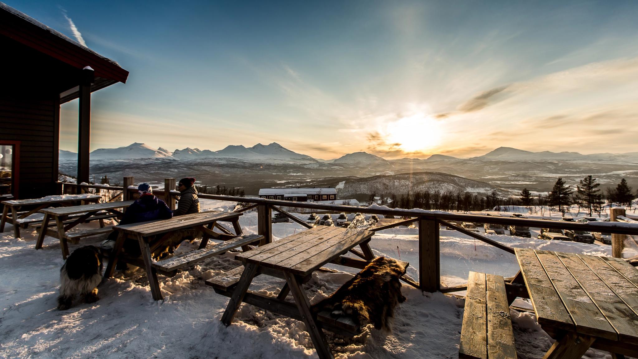 People sitting at some benches outside in Målselv Mountain Village