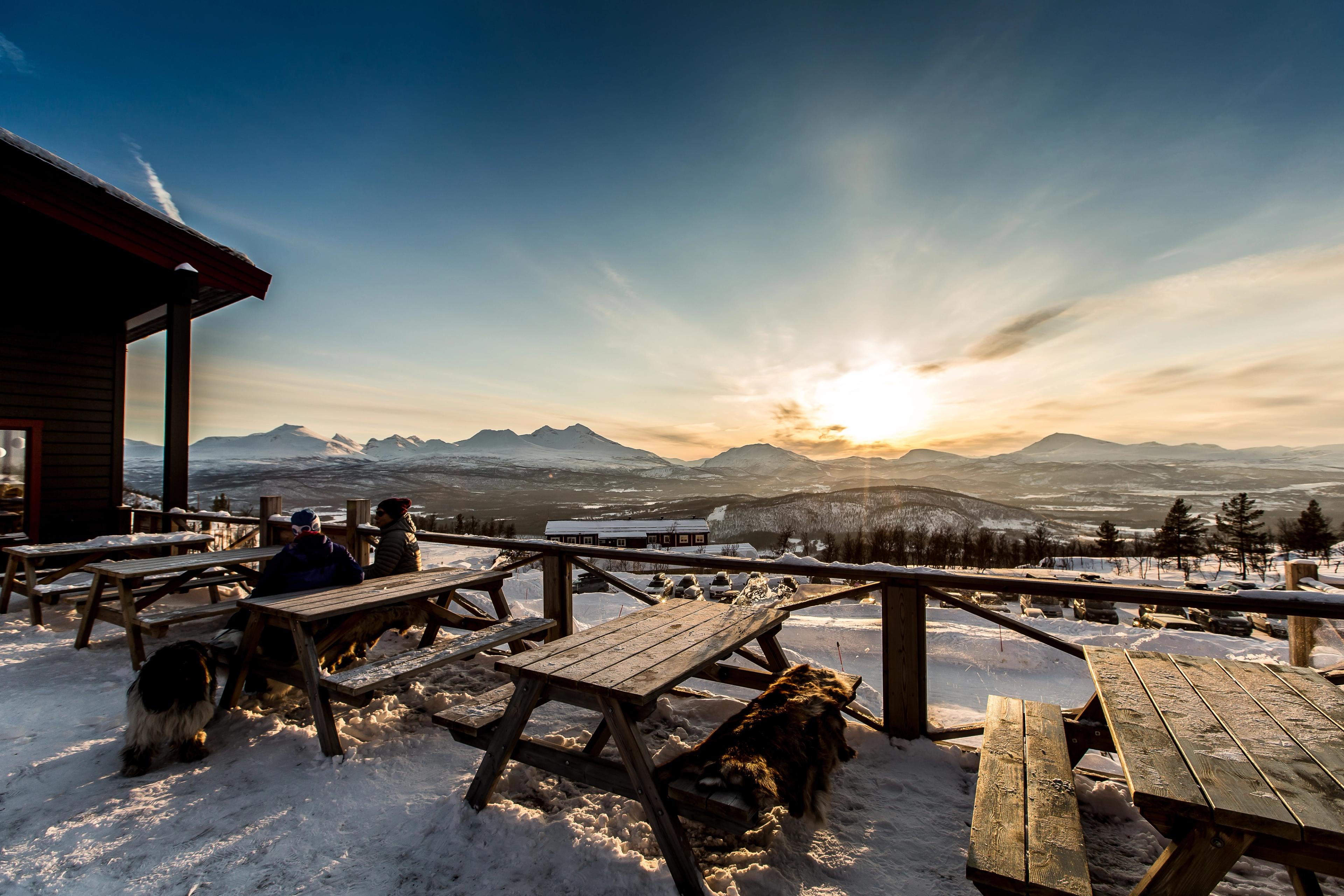 People sitting at some benches outside in Målselv Mountain Village