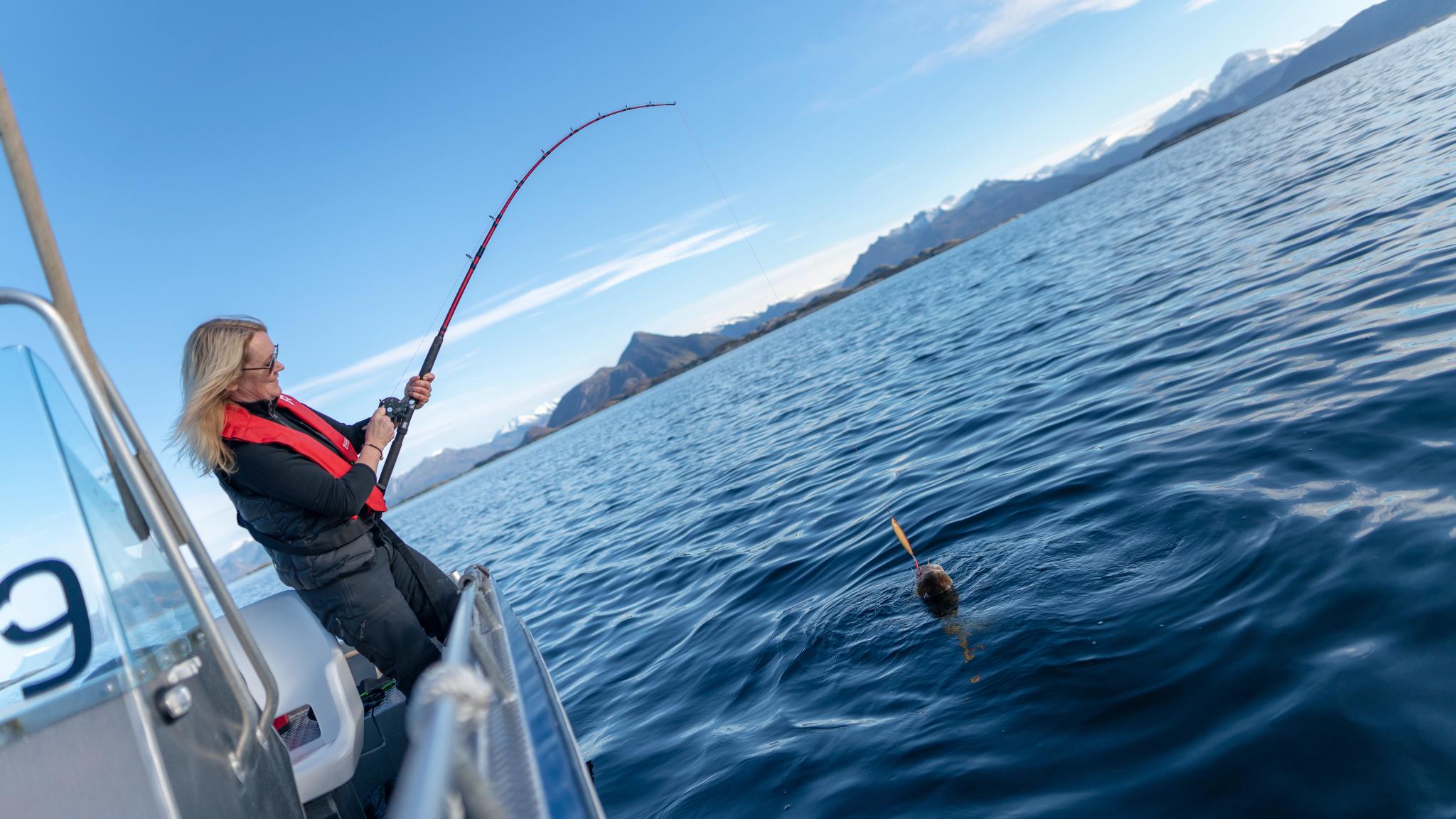 En dame fisker fra en båt utenfor øya Bolga på Helgelandskysten i Nord-Norge