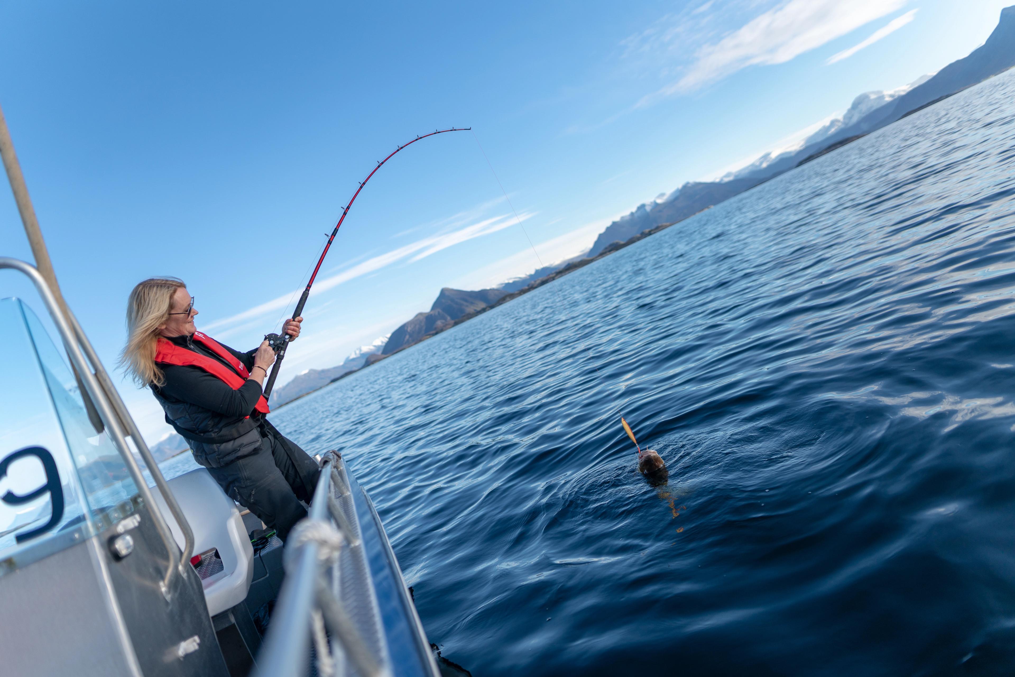 Una mujer pesca desde una barca frente a la costa de Bolga. en Helgeland, Norte de Noruega.