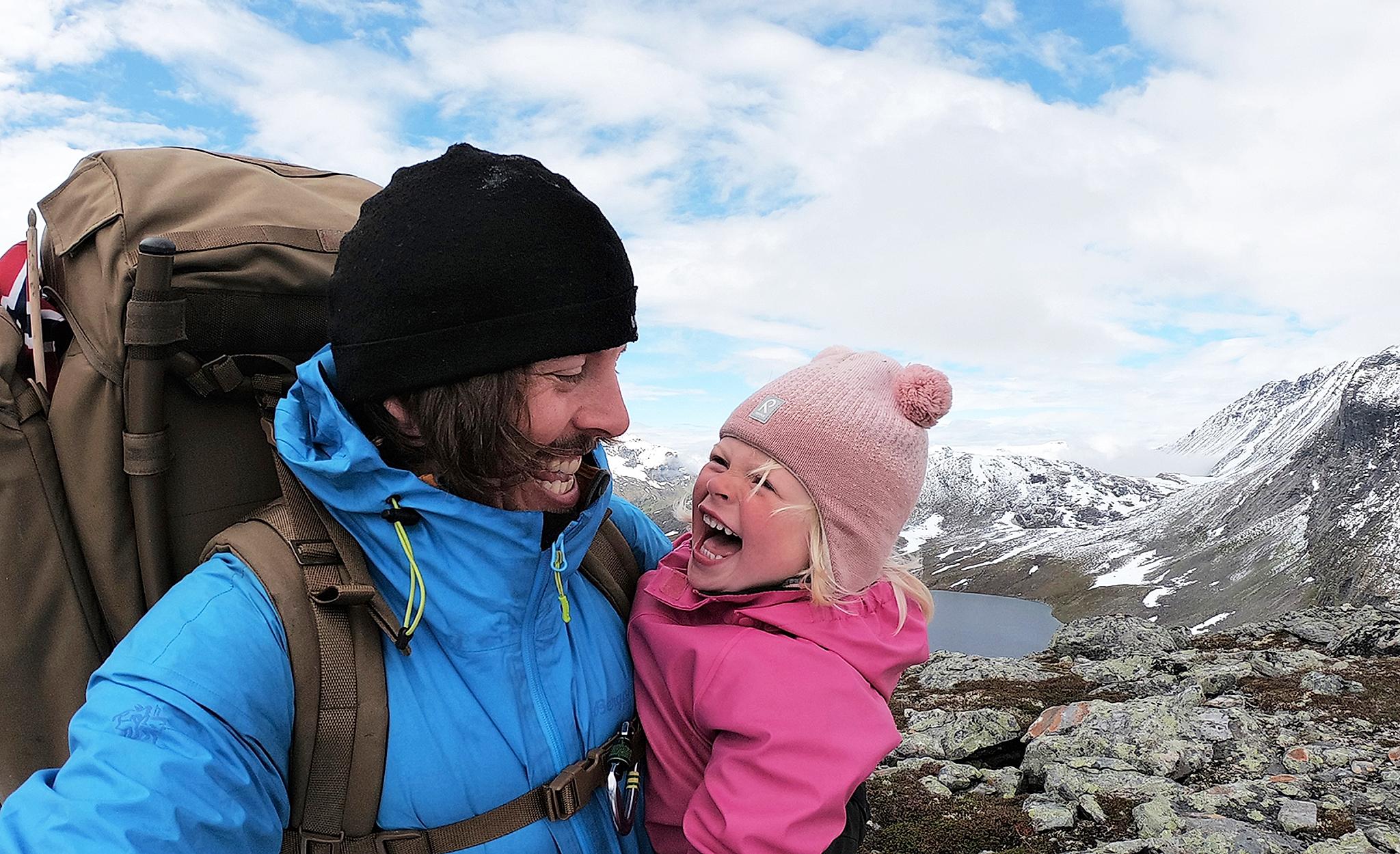 Närbild av ett barn och hennes pappa på vandringstur i Hjørundfjorden i regionen Fjord Norge (Vestlandet)