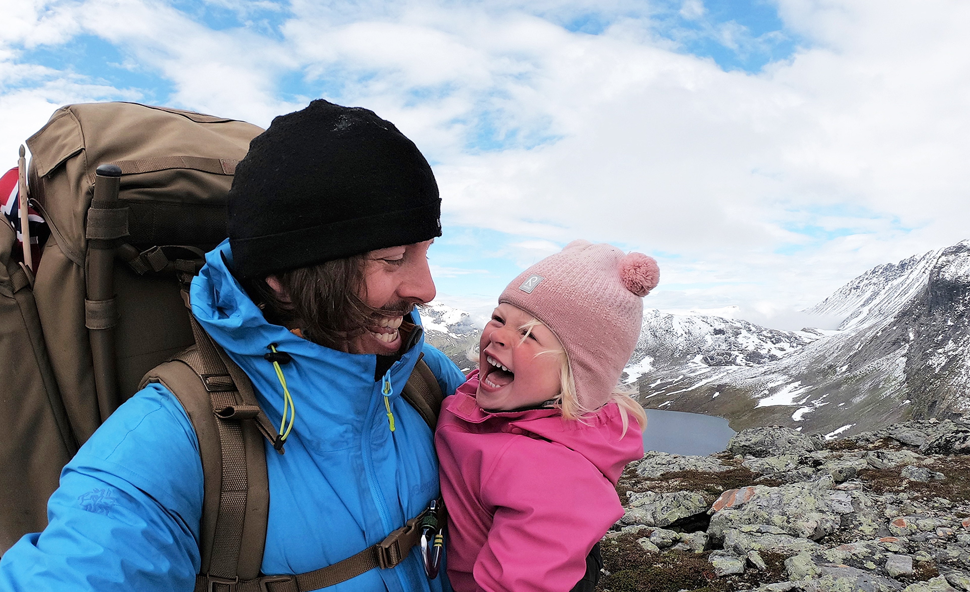 Nahaufnahmebild eines jungen Mädchens und ihres Vaters, die sich auf einer Wanderung anlächeln, Hjørundfjord, Fjord Norwegen