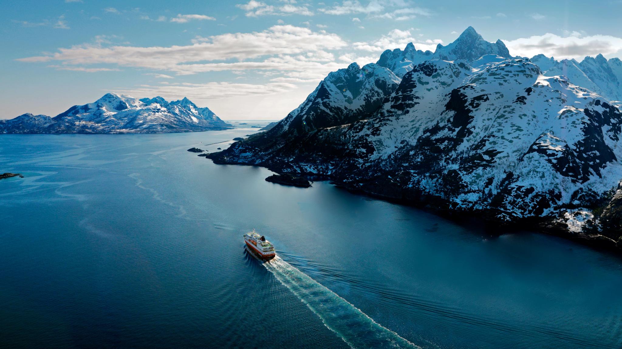 Hurtigruten in a fjord sailing past mountains
