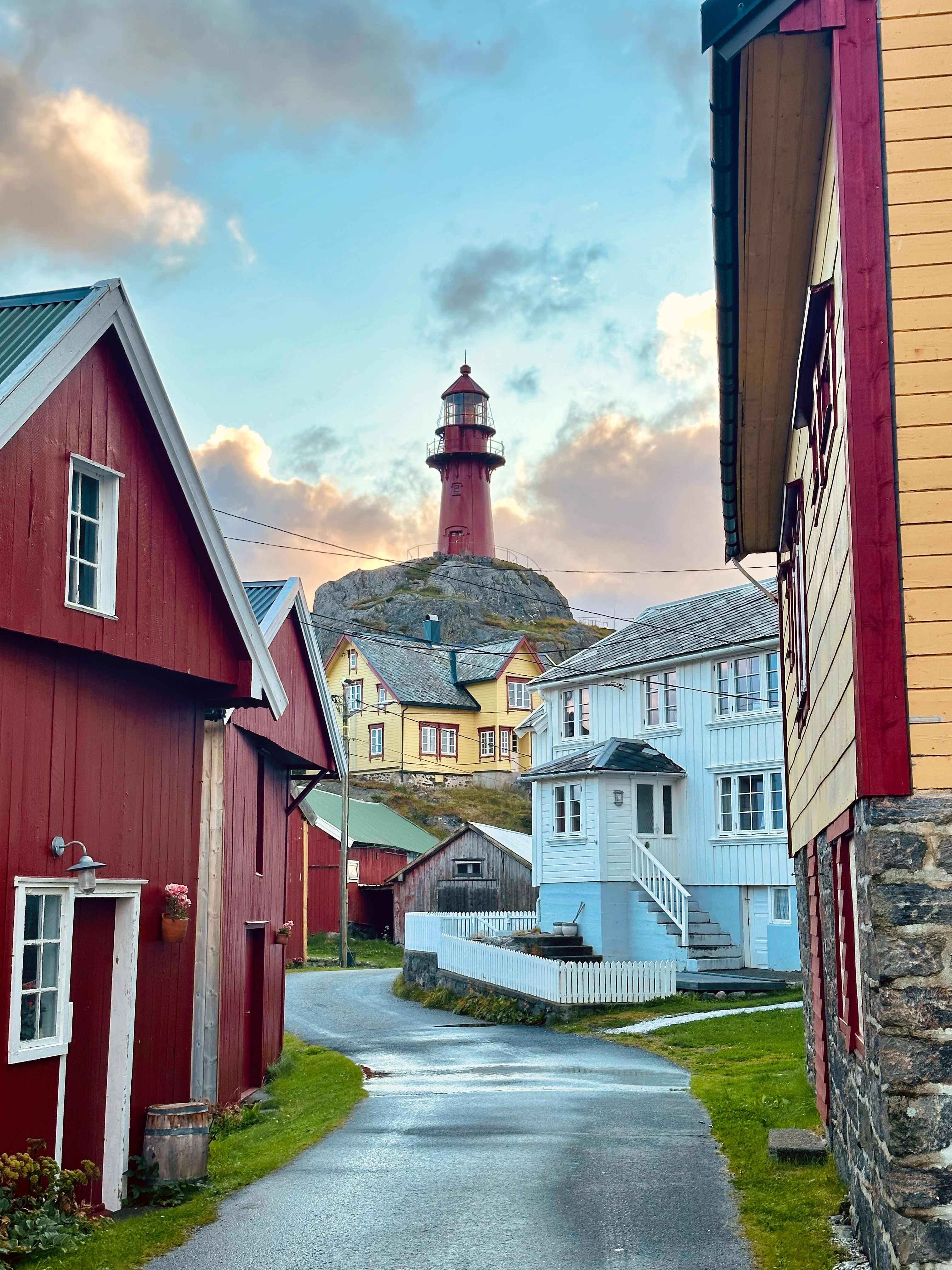 One of the cosy streets at the island Ona, with great view of the tall, red Ona lighthouse in Fjord Norway