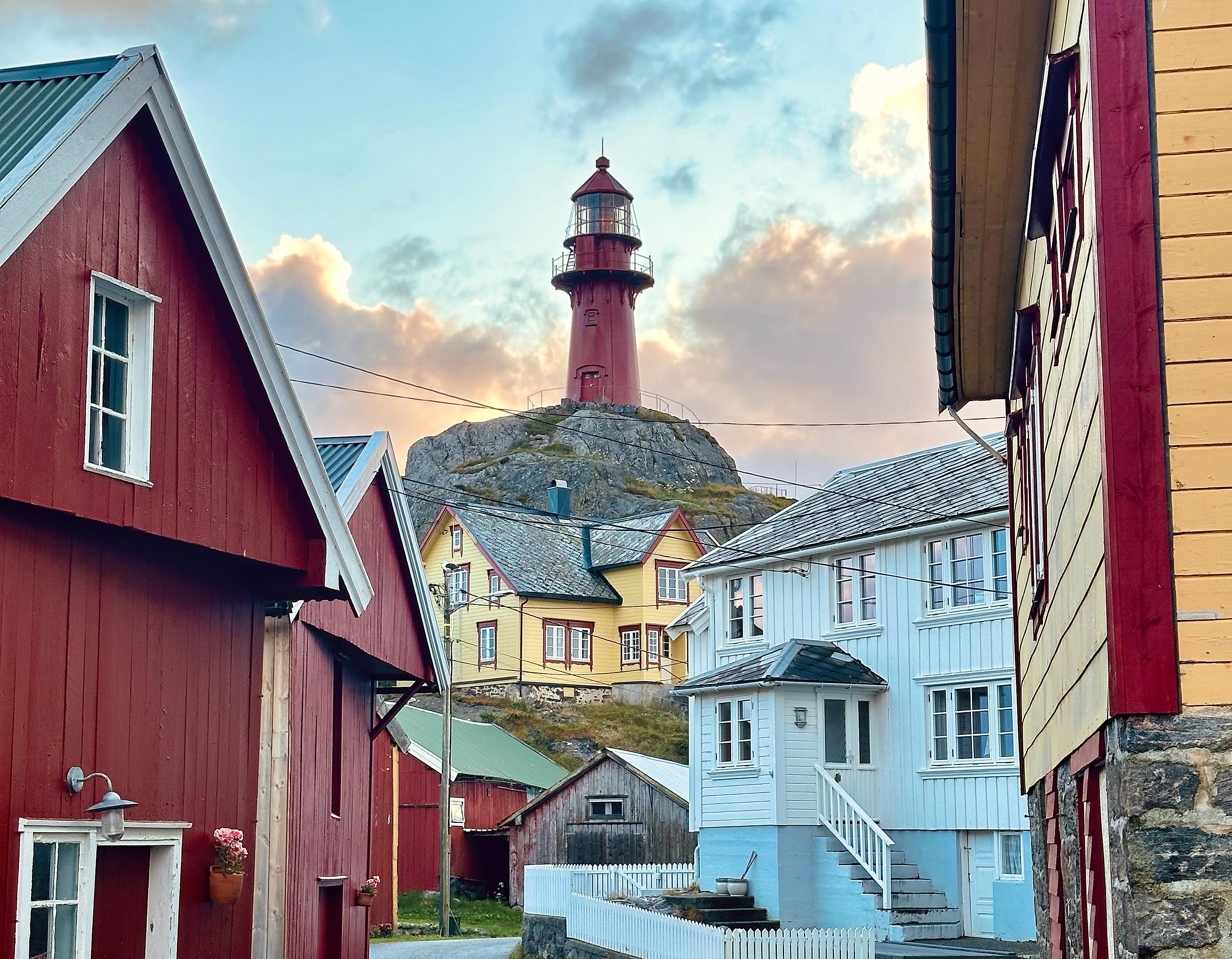One of the cosy streets at the island Ona, with great view of the tall, red Ona lighthouse in Fjord Norway
