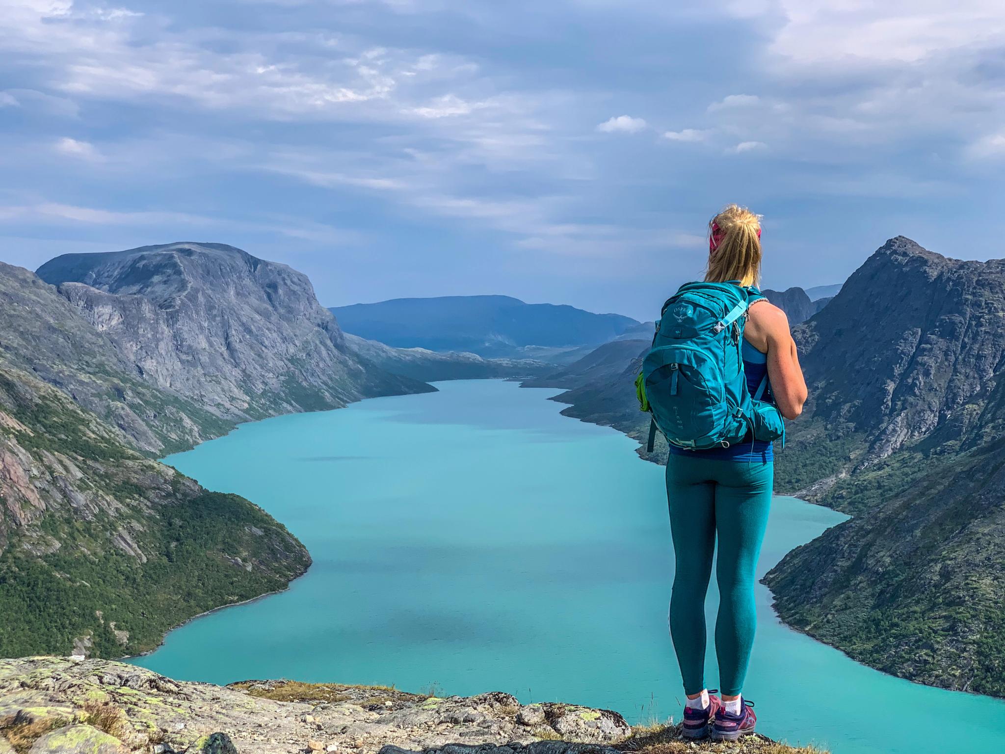 A woman looking a the view of a lake from the top of a mountain