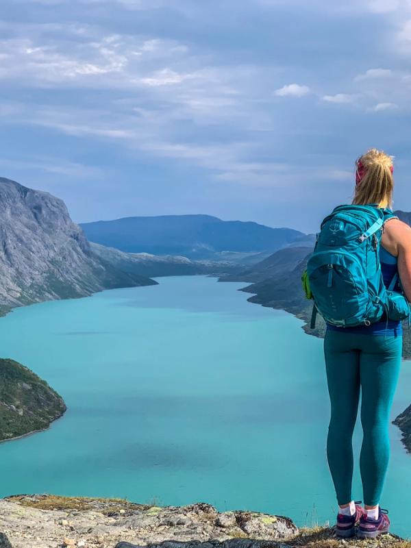 A woman looking a the view of a lake from the top of a mountain