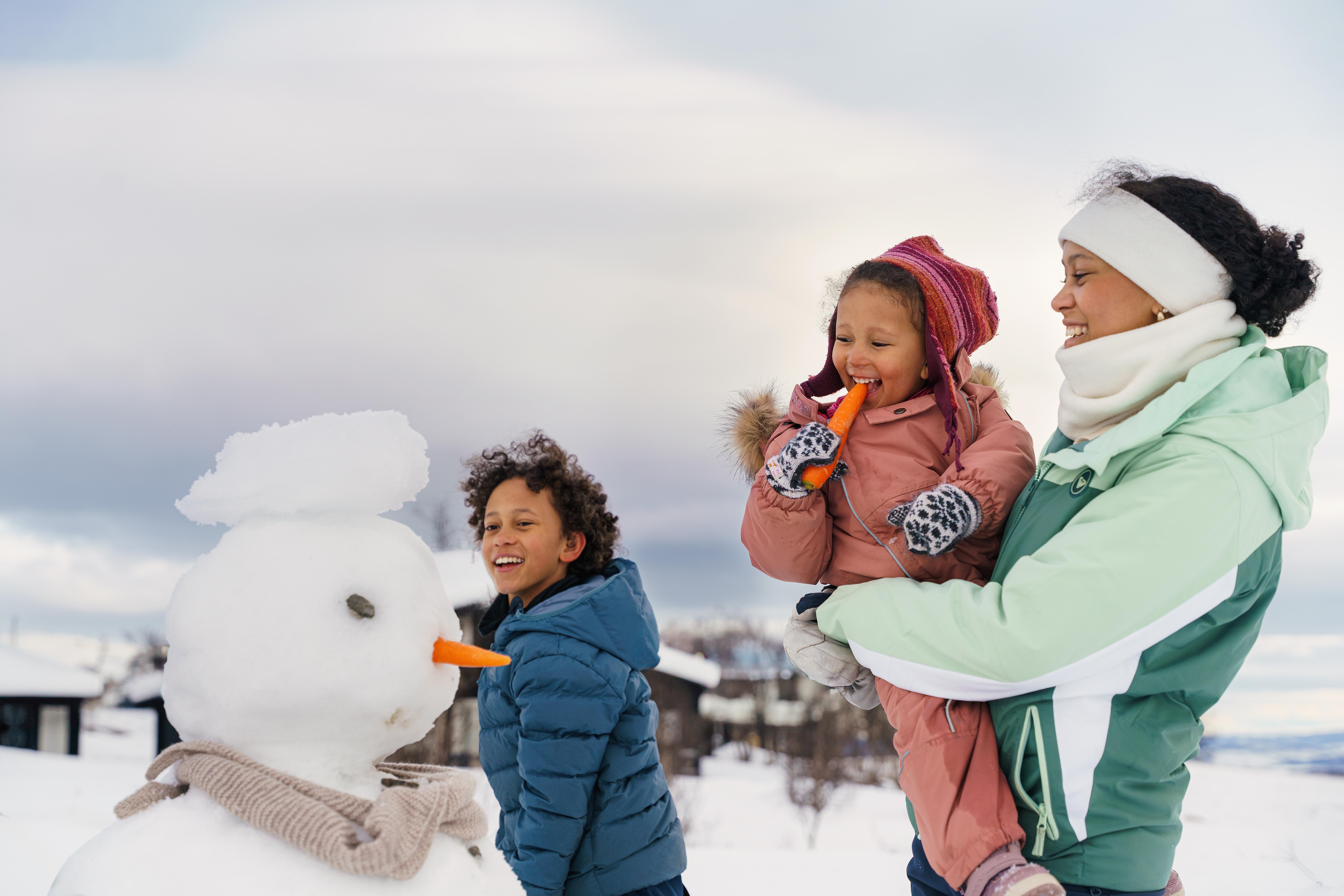Tree kids of different ages are making a snowman in Beitostølen, Norway