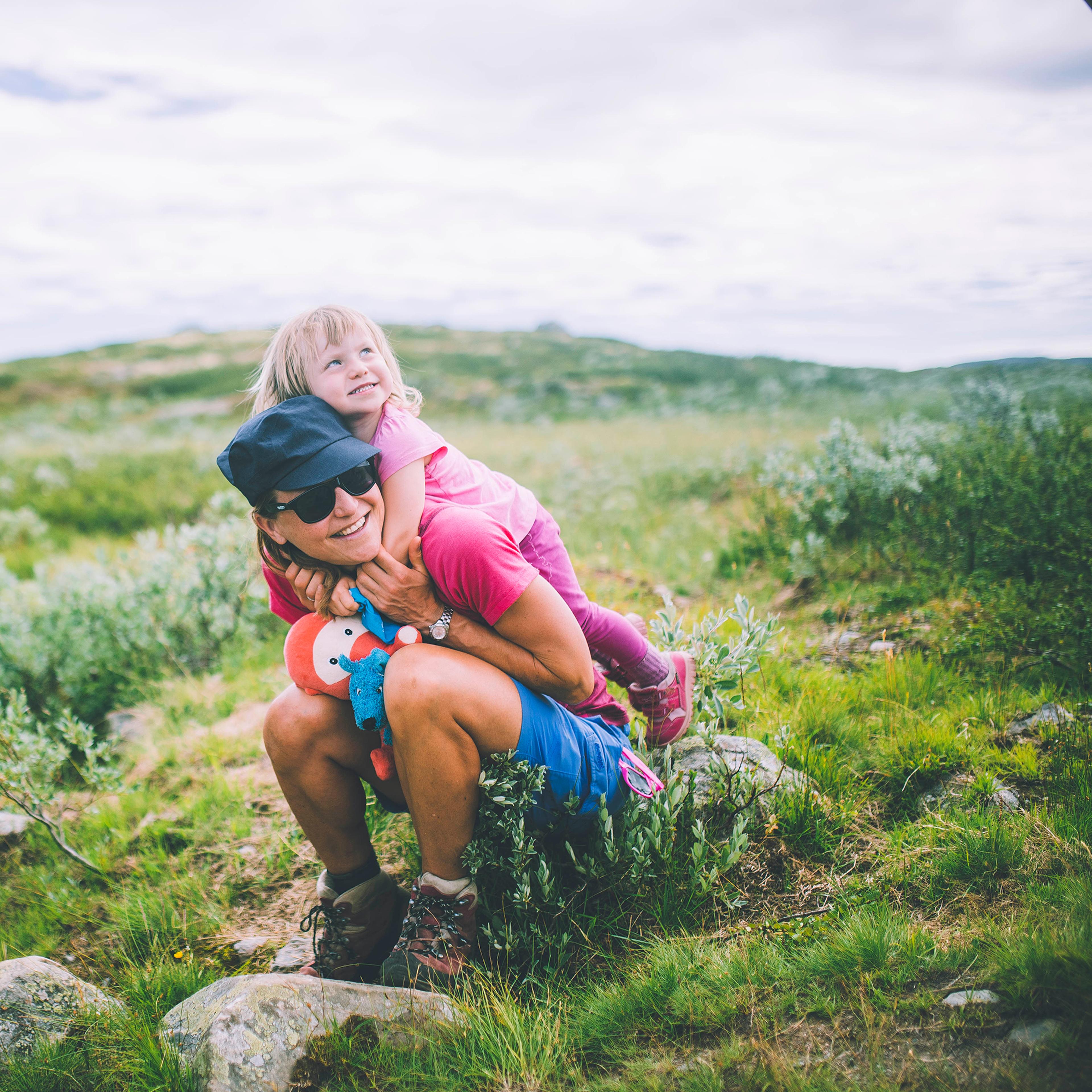 Mother sitting with her daughter on her back in Hardangervidda national park in Norway