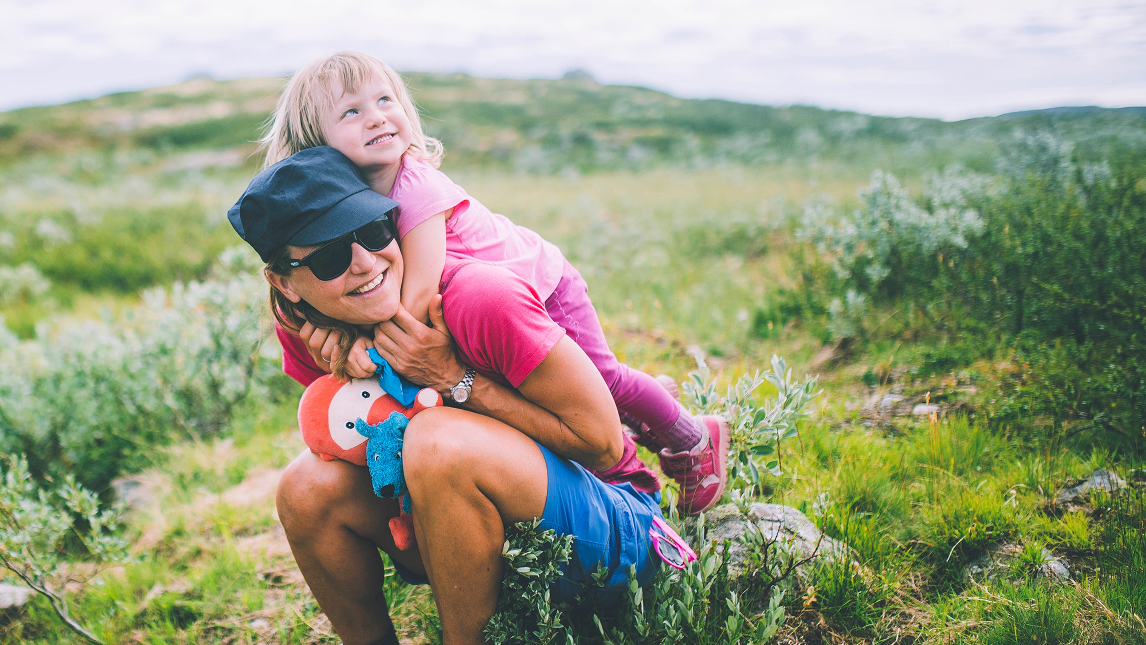 Mother sitting with her daughter on her back in Hardangervidda national park in Norway
