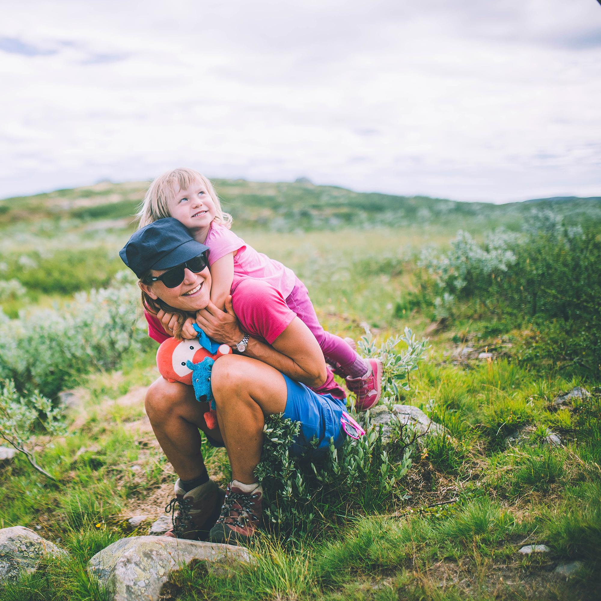 Mother sitting with her daughter on her back in Hardangervidda national park in Norway