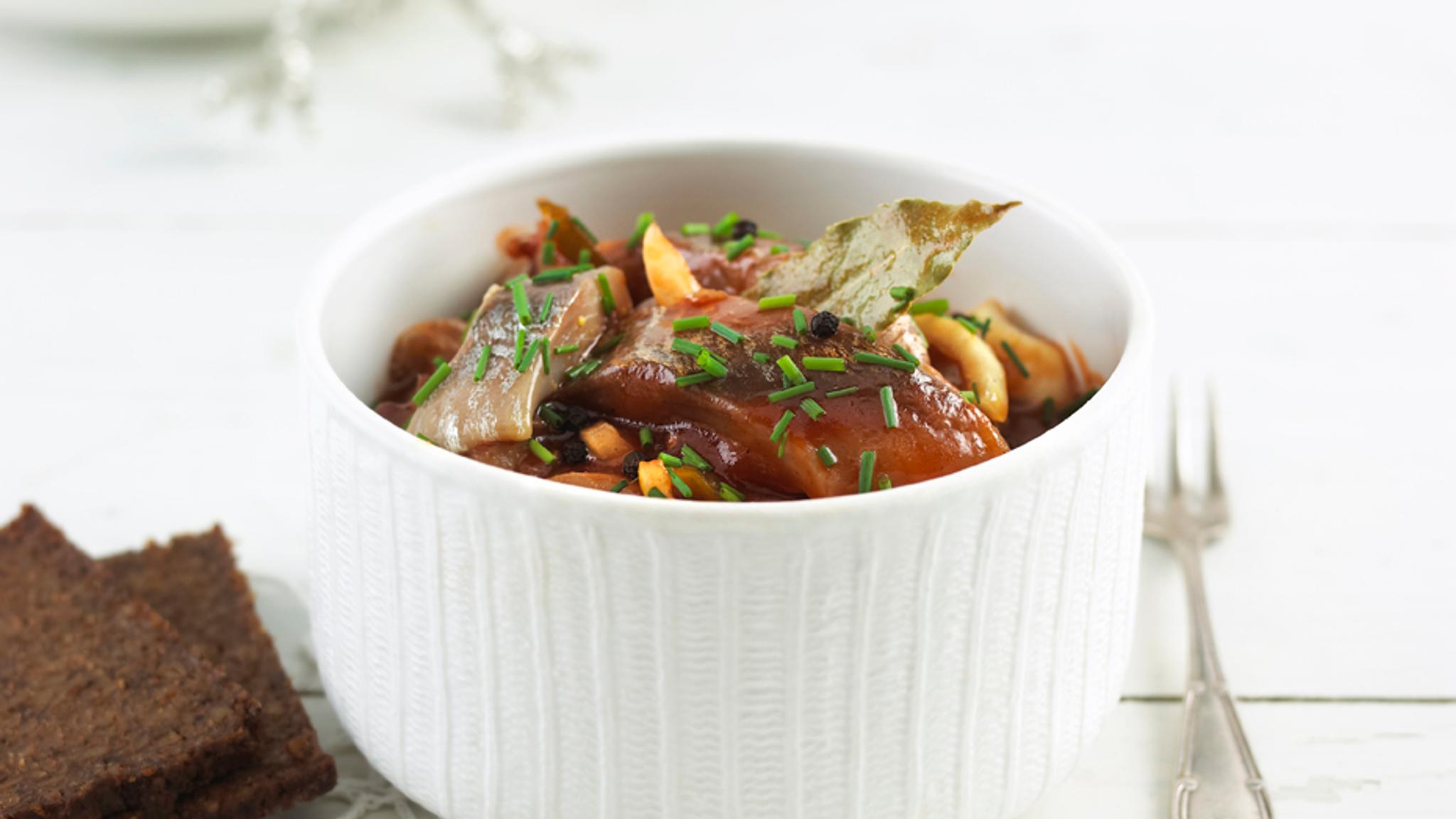 Traditional Norwegian pickled herring in tomato sauce in a glass jar