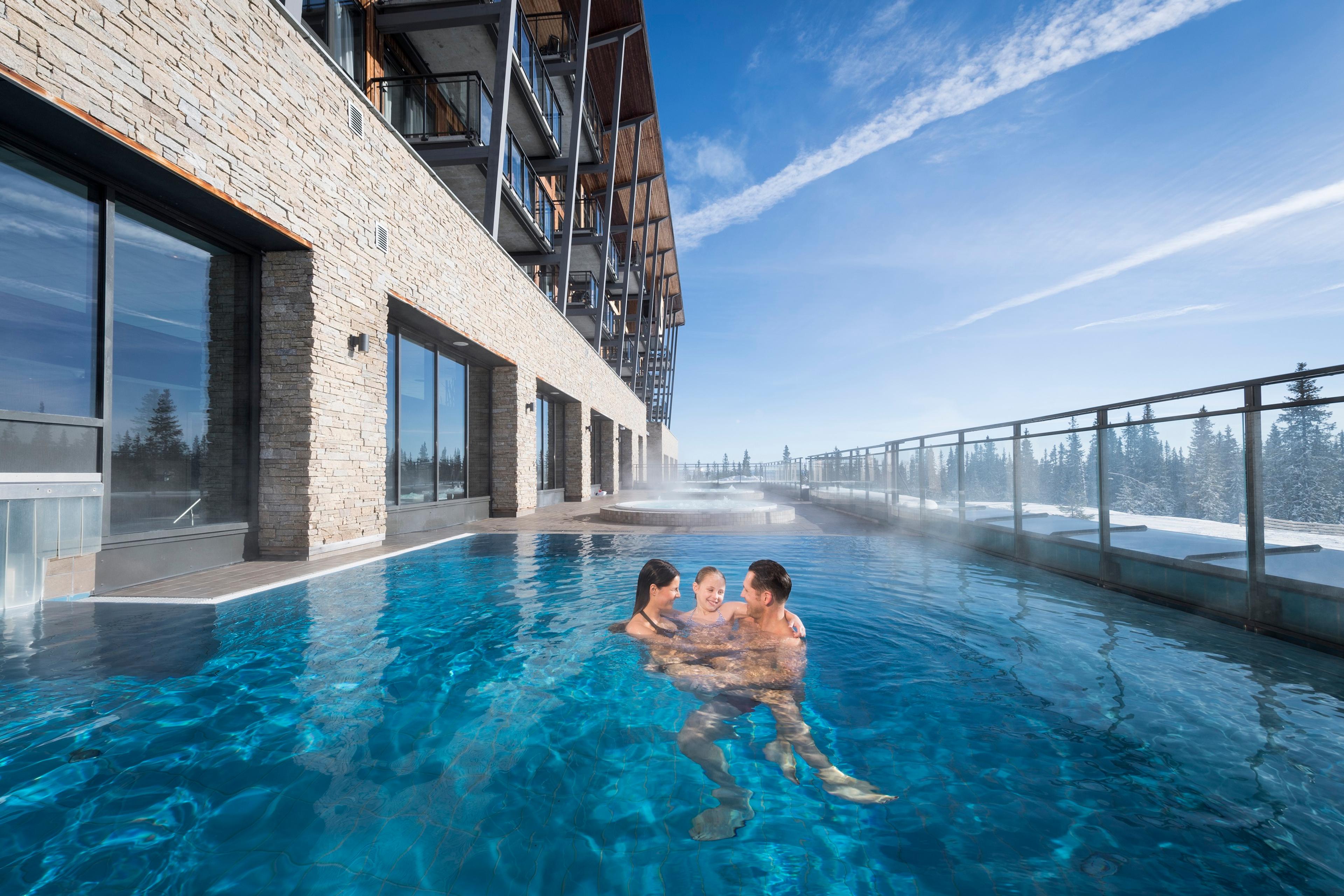 Family in outdoor pool in winter at Radisson Blu mountain resort & residences in Trysil, Eastern Norway