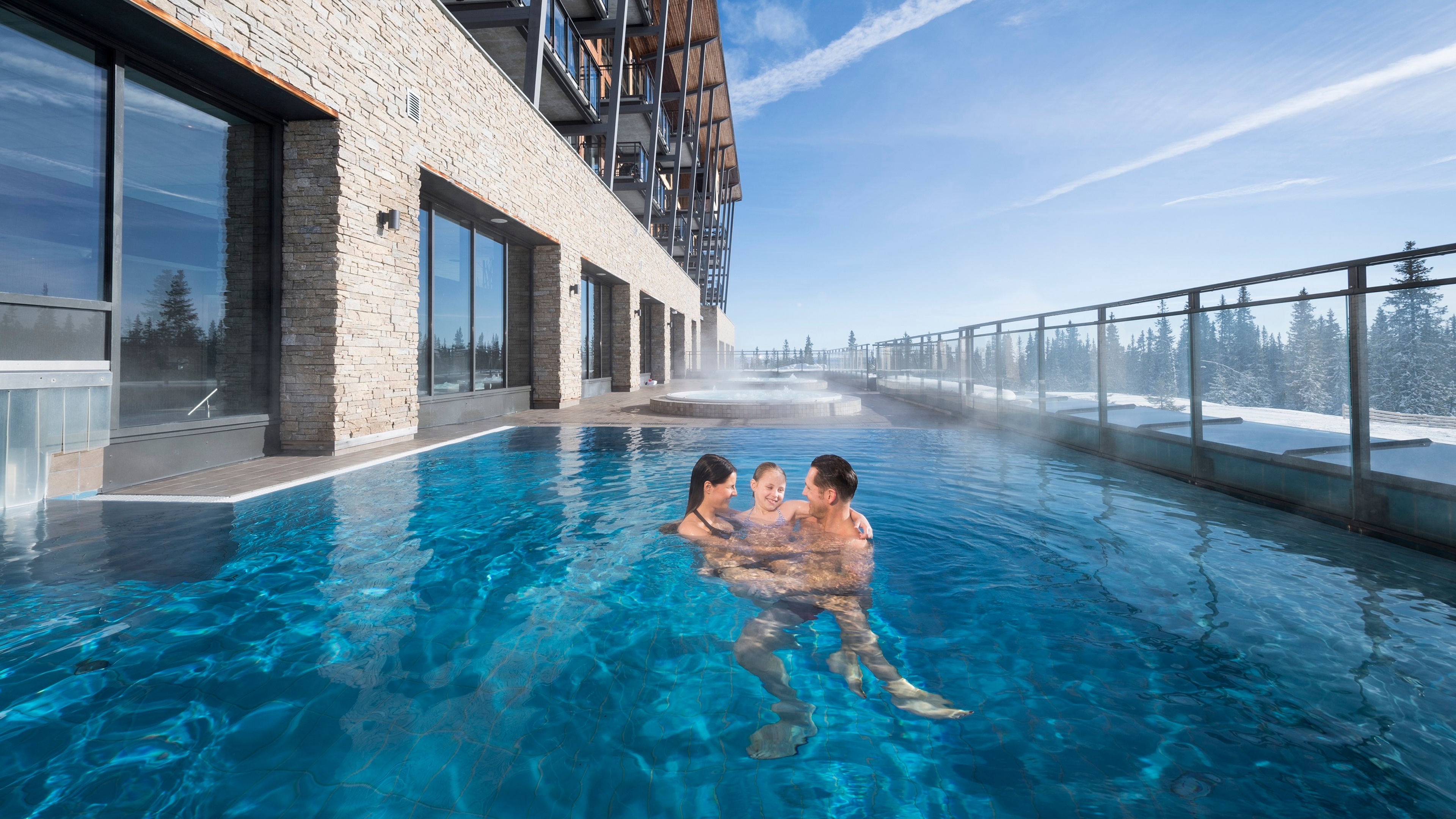 Family in outdoor pool in winter at Radisson Blu mountain resort & residences in Trysil, Eastern Norway