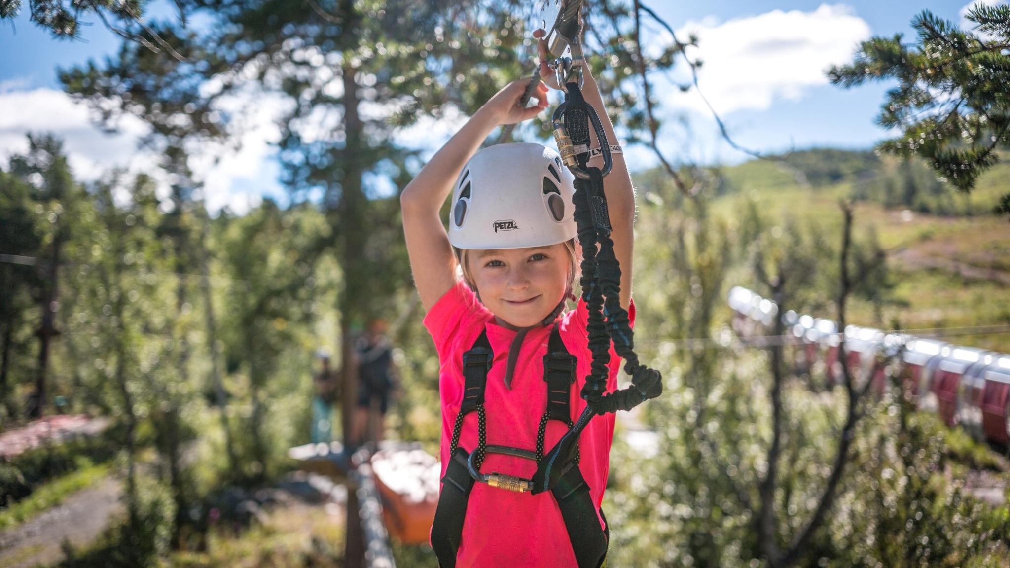 A young girl balancing between treetops in the high-rope course in Geilo sommerpark, Eastern Norway