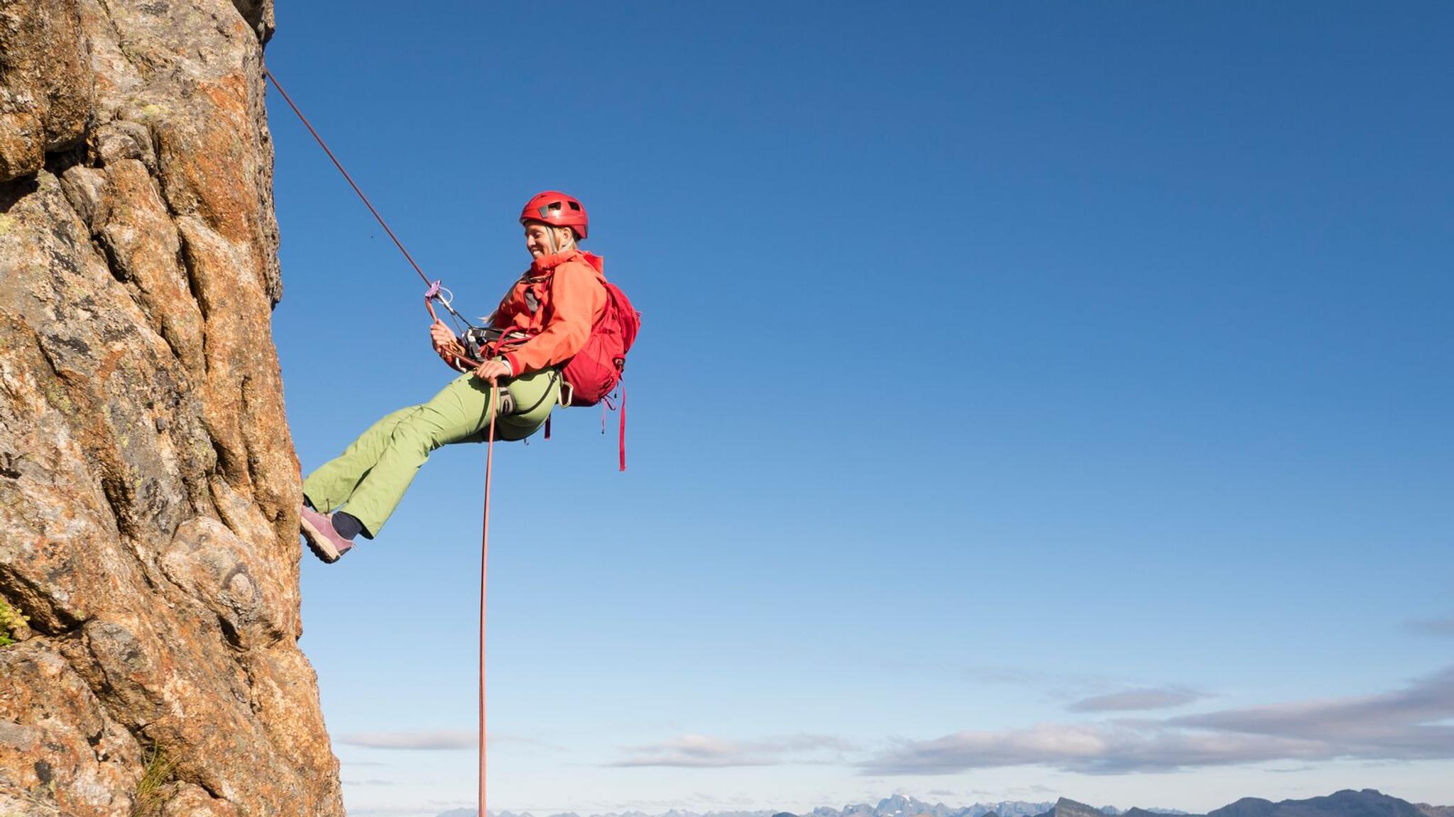 Dame som rappellerer ned fjellet "Reka" i Vesterålen, Nord-Norge