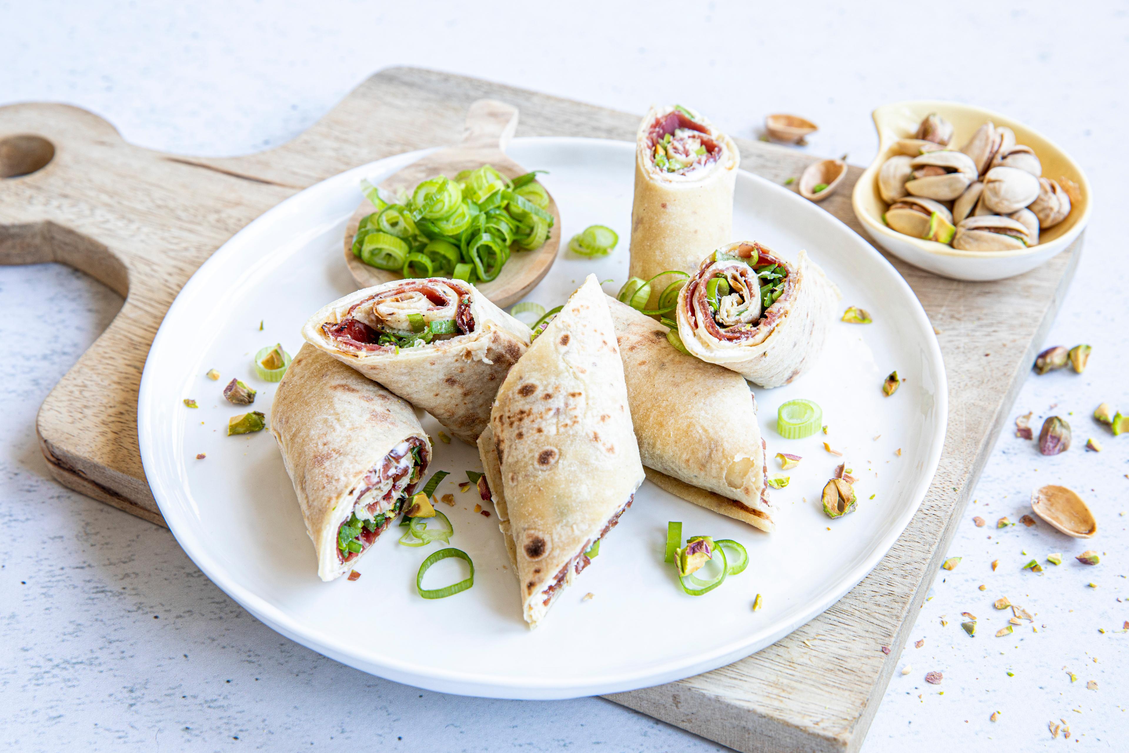 A plate with flatbread roll-ups with fenalår and pistachios