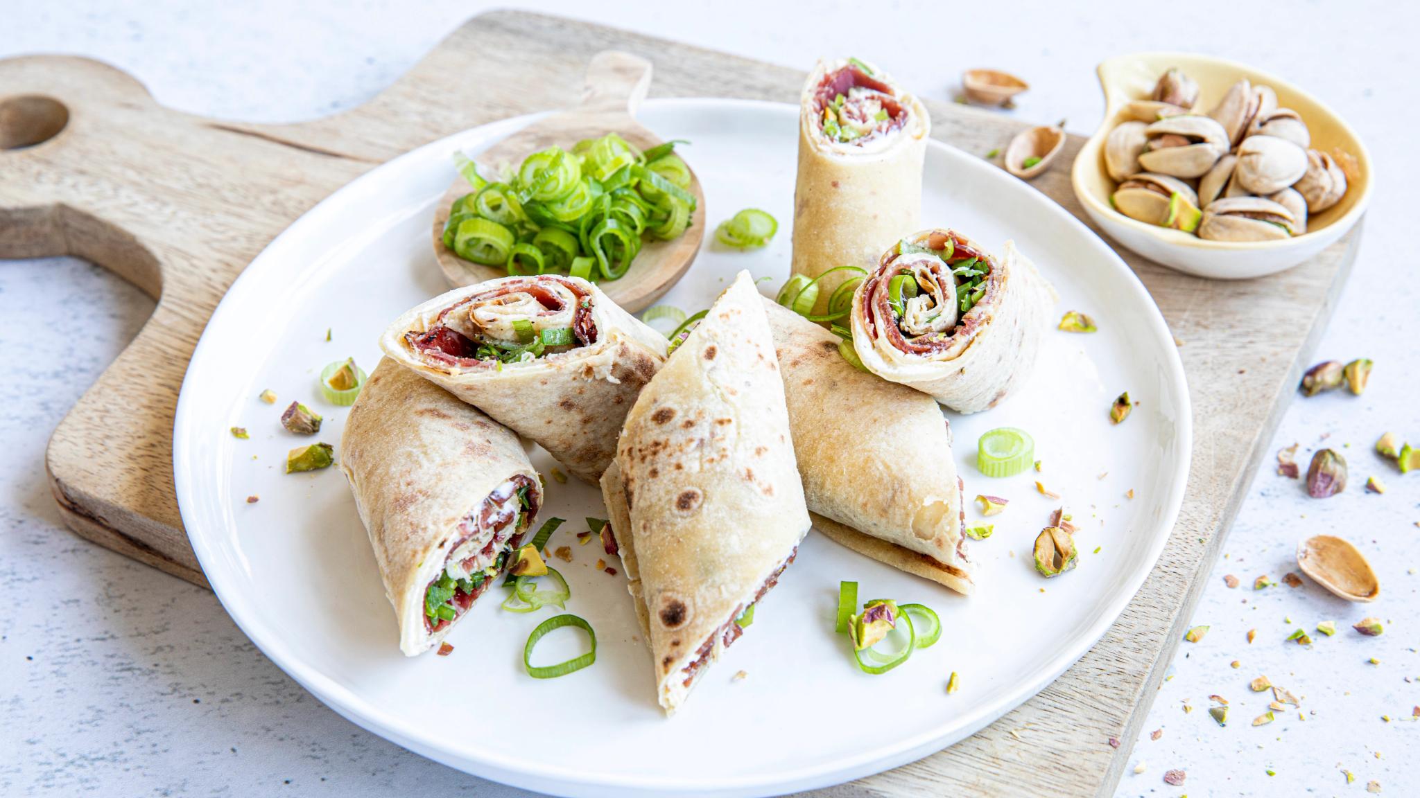 A plate with flatbread roll-ups with fenalår and pistachios