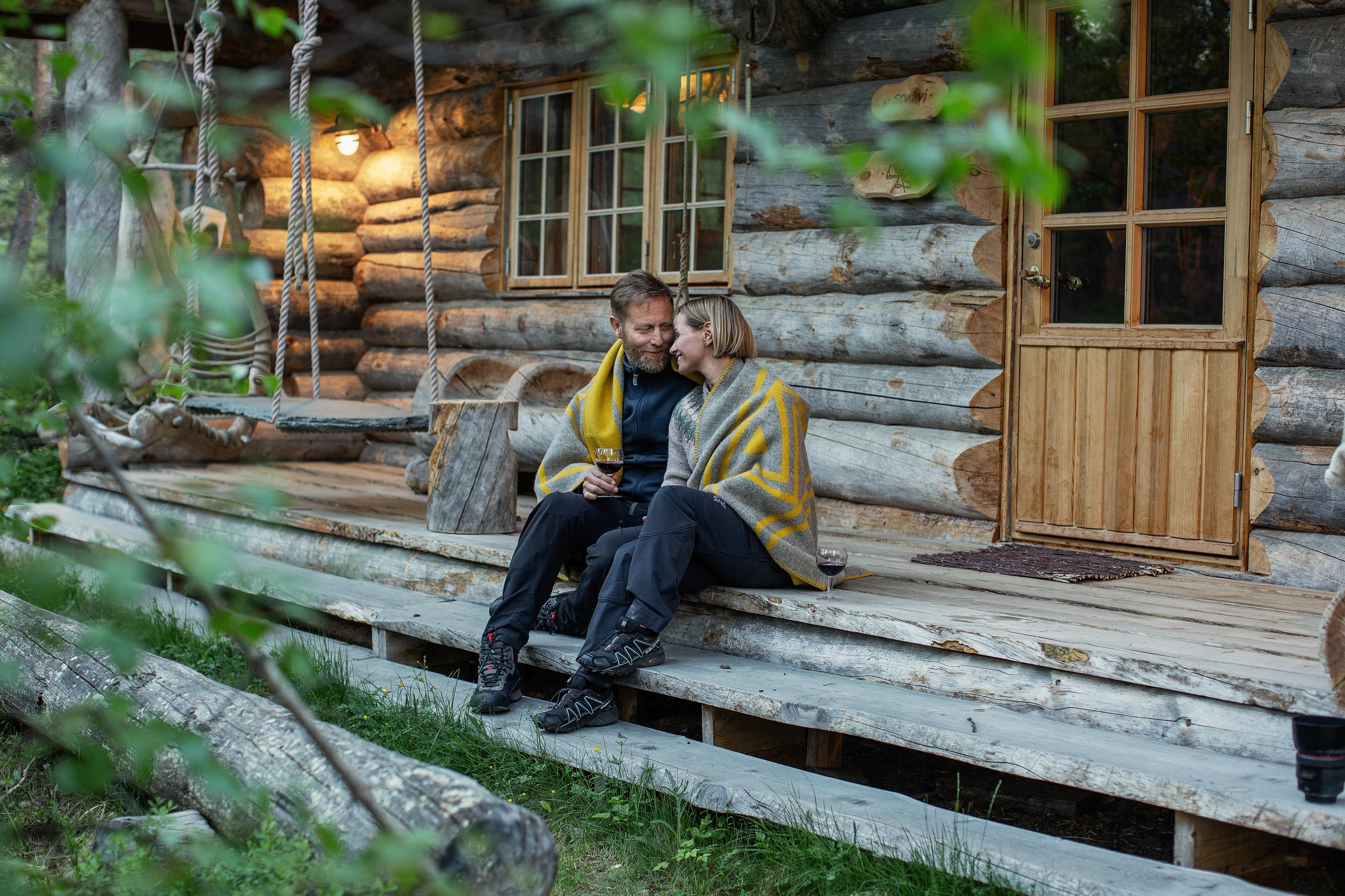 A couple on the steps outside a Engholm Design Lodge in Karasjok