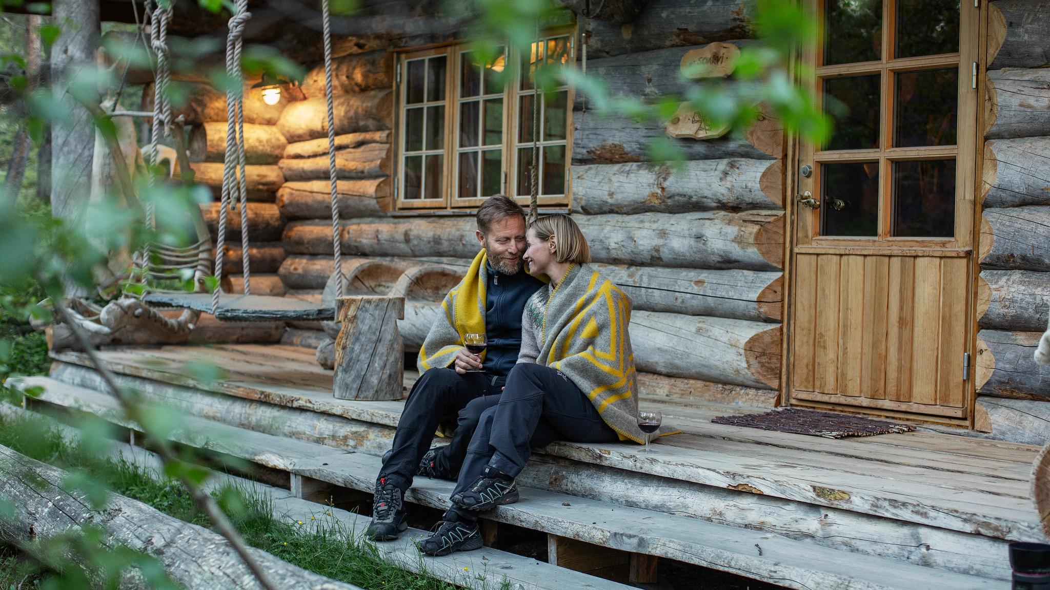 A couple on the steps outside a Engholm Design Lodge in Karasjok
