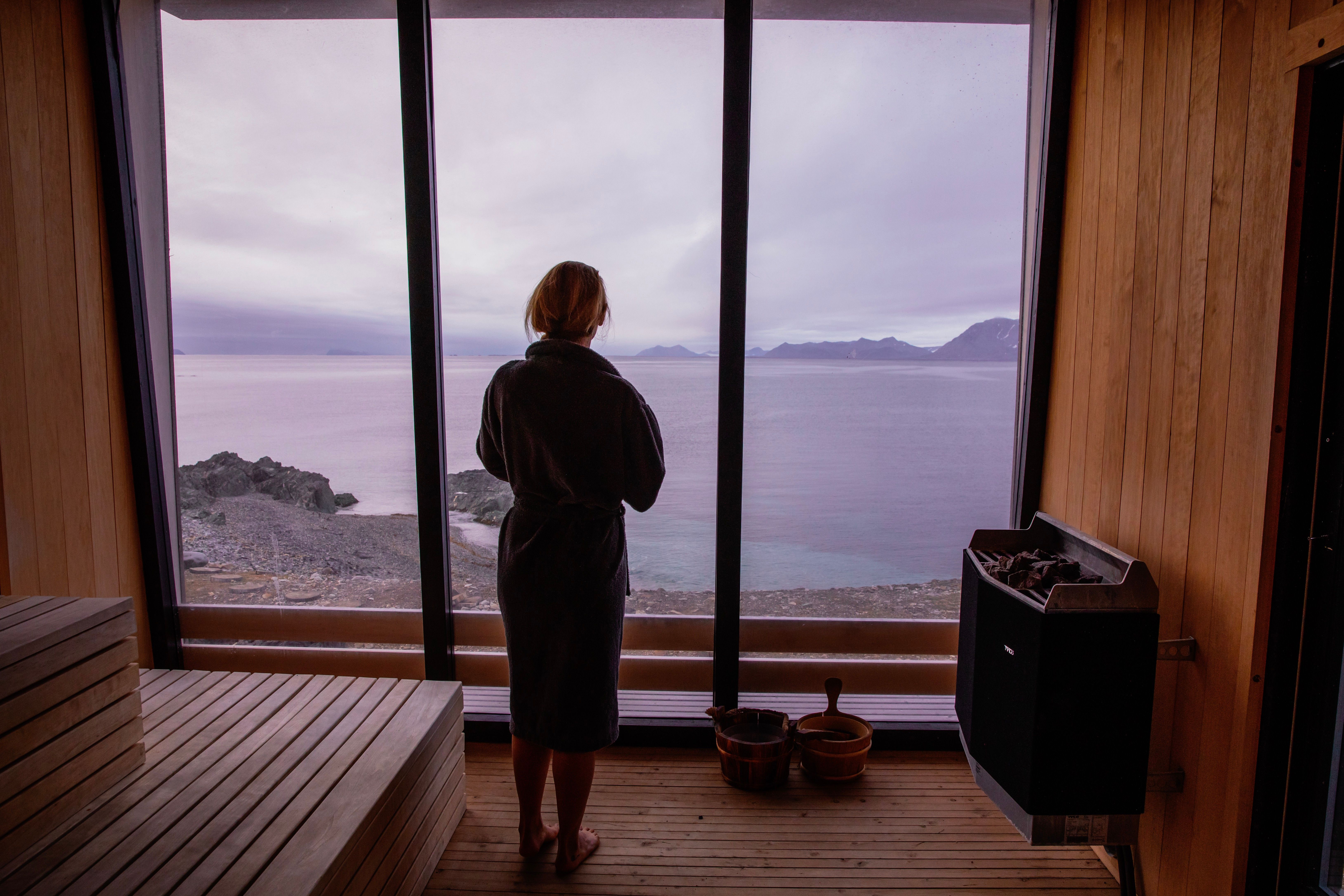 A woman looking out of the window of the sauna at Isfjord Radio Adventure Hotel in Spitsbergen in Svalbard, Norway