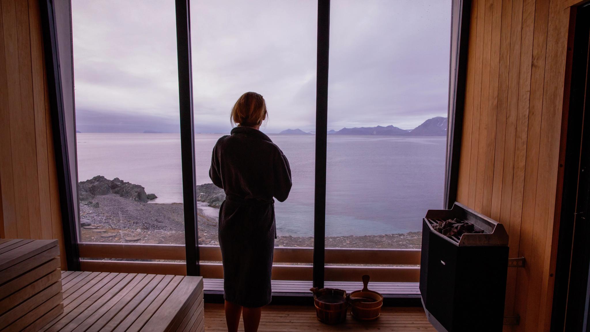 A woman looking out of the window of the sauna at Isfjord Radio Adventure Hotel in Spitsbergen in Svalbard, Norway
