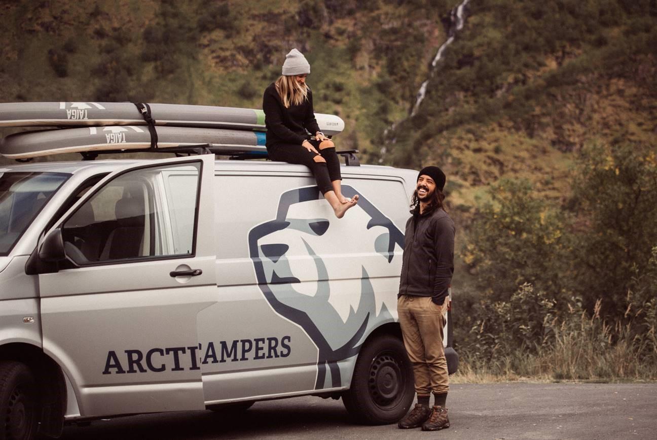Couple on a trip, girl sitting on a roof of Arctic Camper