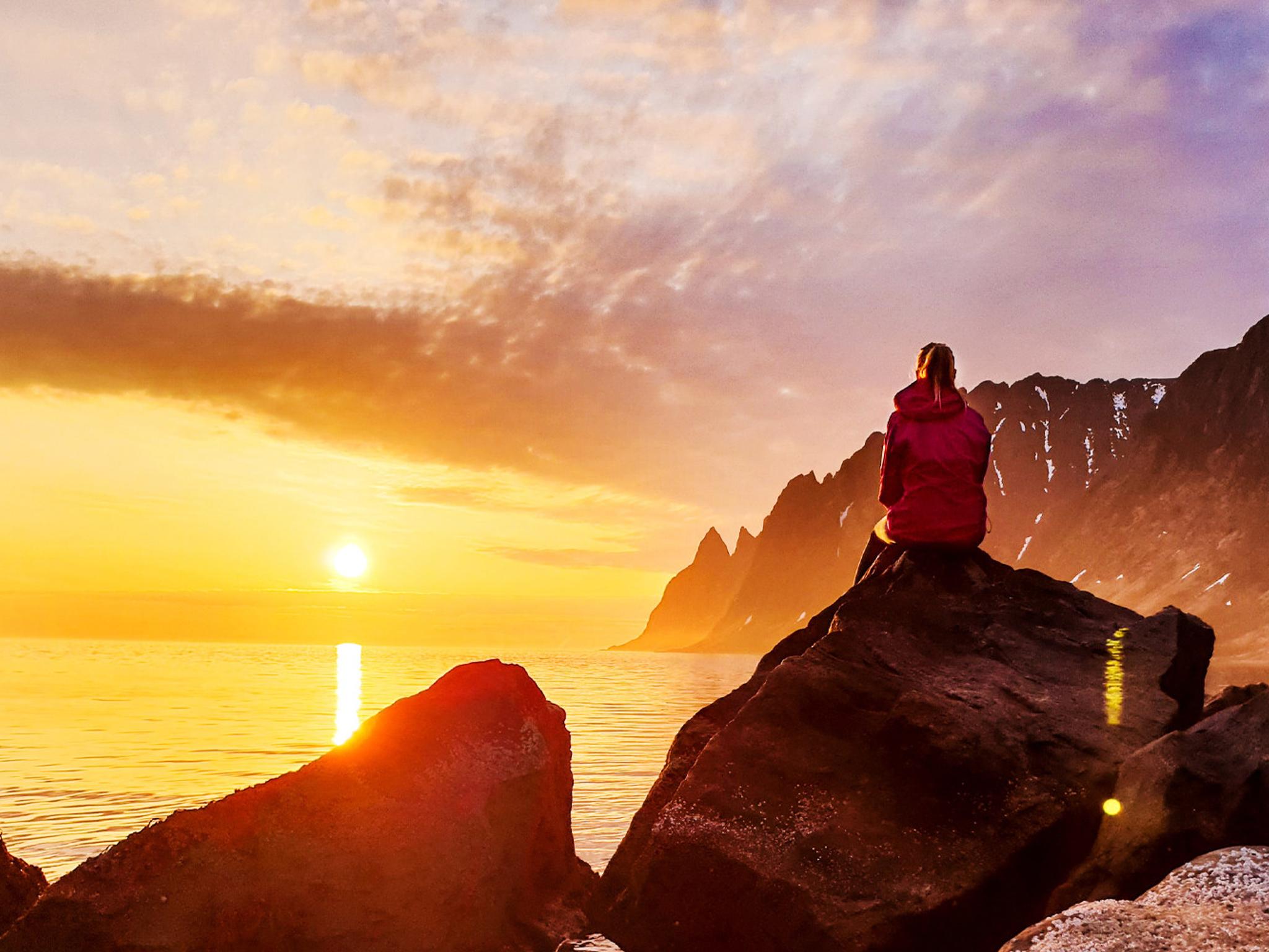 En person tar in midnattssolen i Senja i Nord-Norge