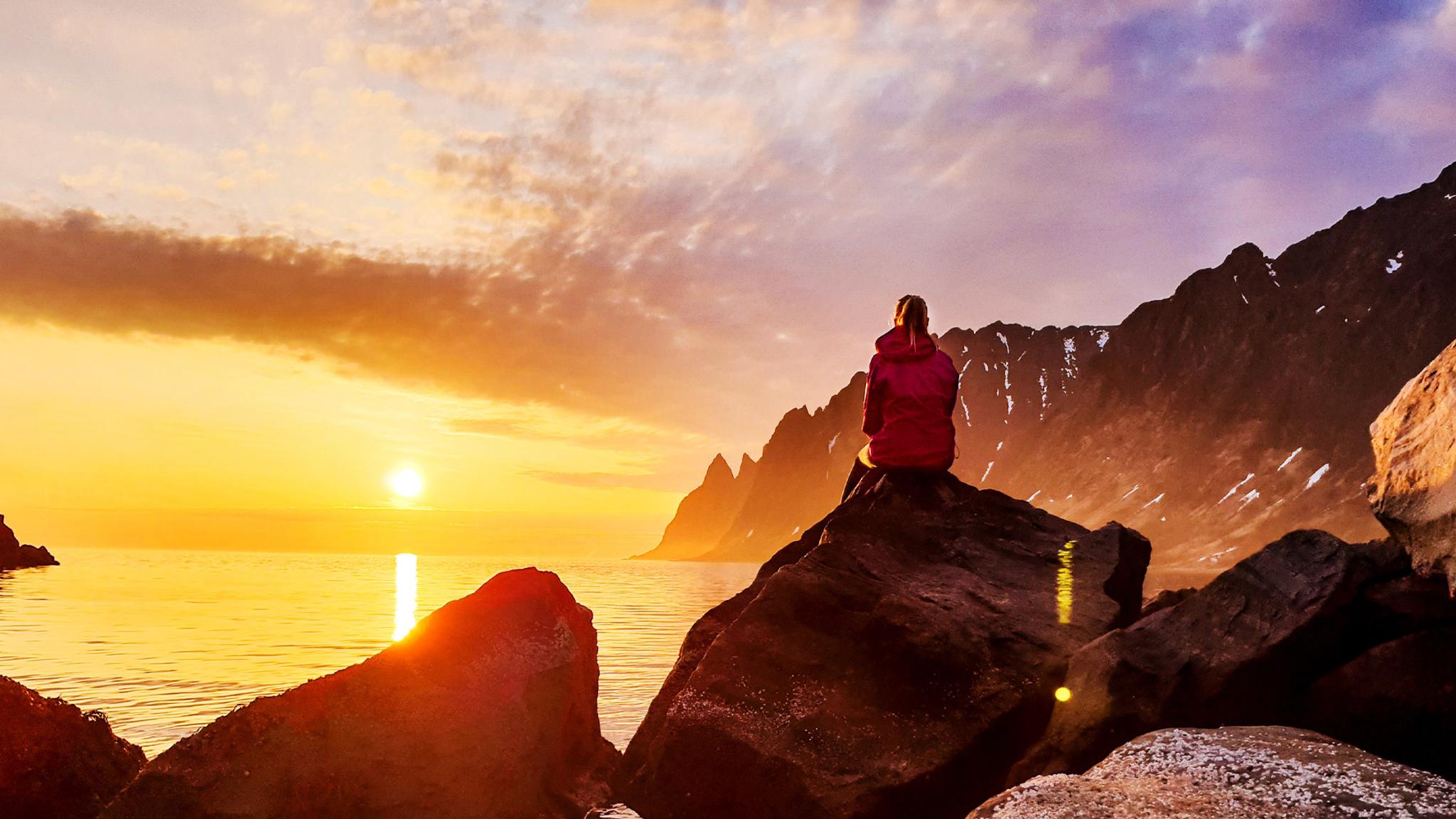A person watching the midnight sun at Senja in Northern Norway